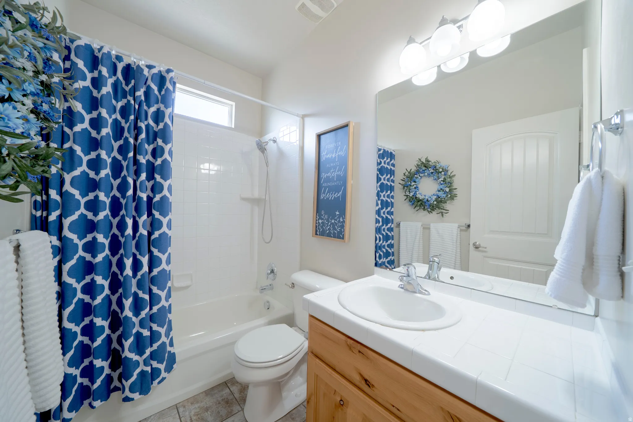 Full bathroom featuring vanity, shower / bath combo with shower curtain, and light tile patterned floors
