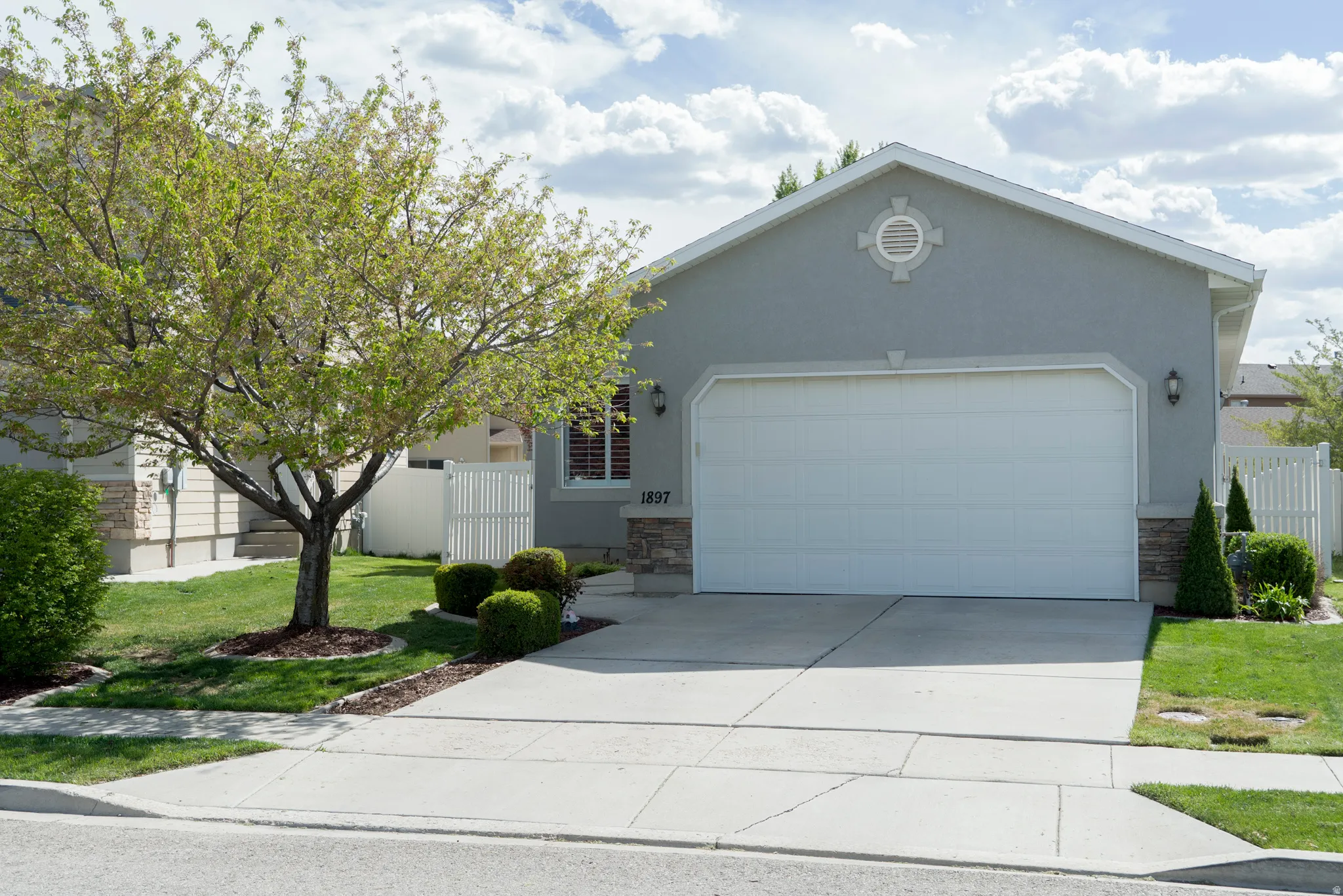 Single story home featuring stone siding, a garage, concrete driveway, and stucco siding