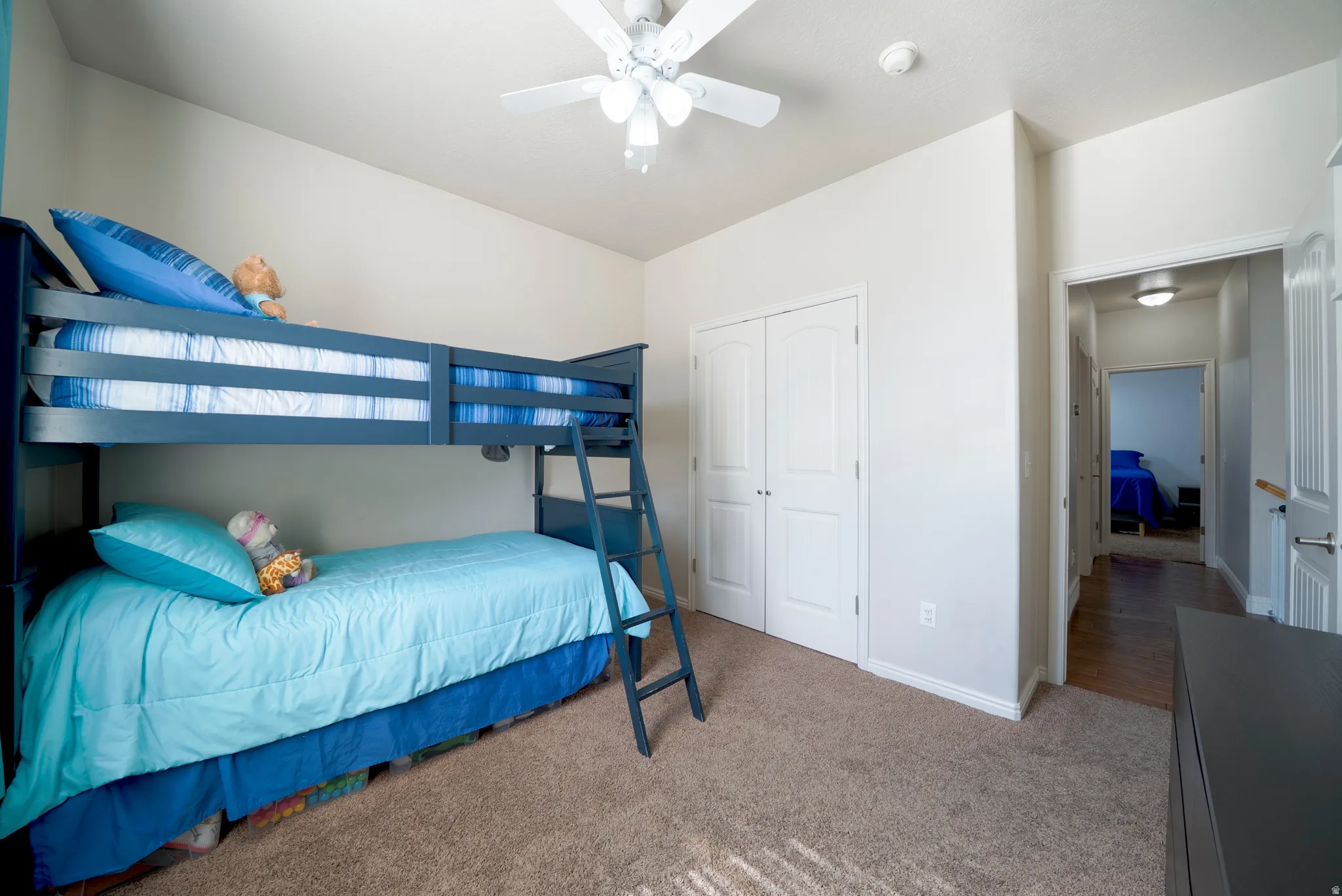 Bedroom featuring light colored carpet, a ceiling fan, and a closet