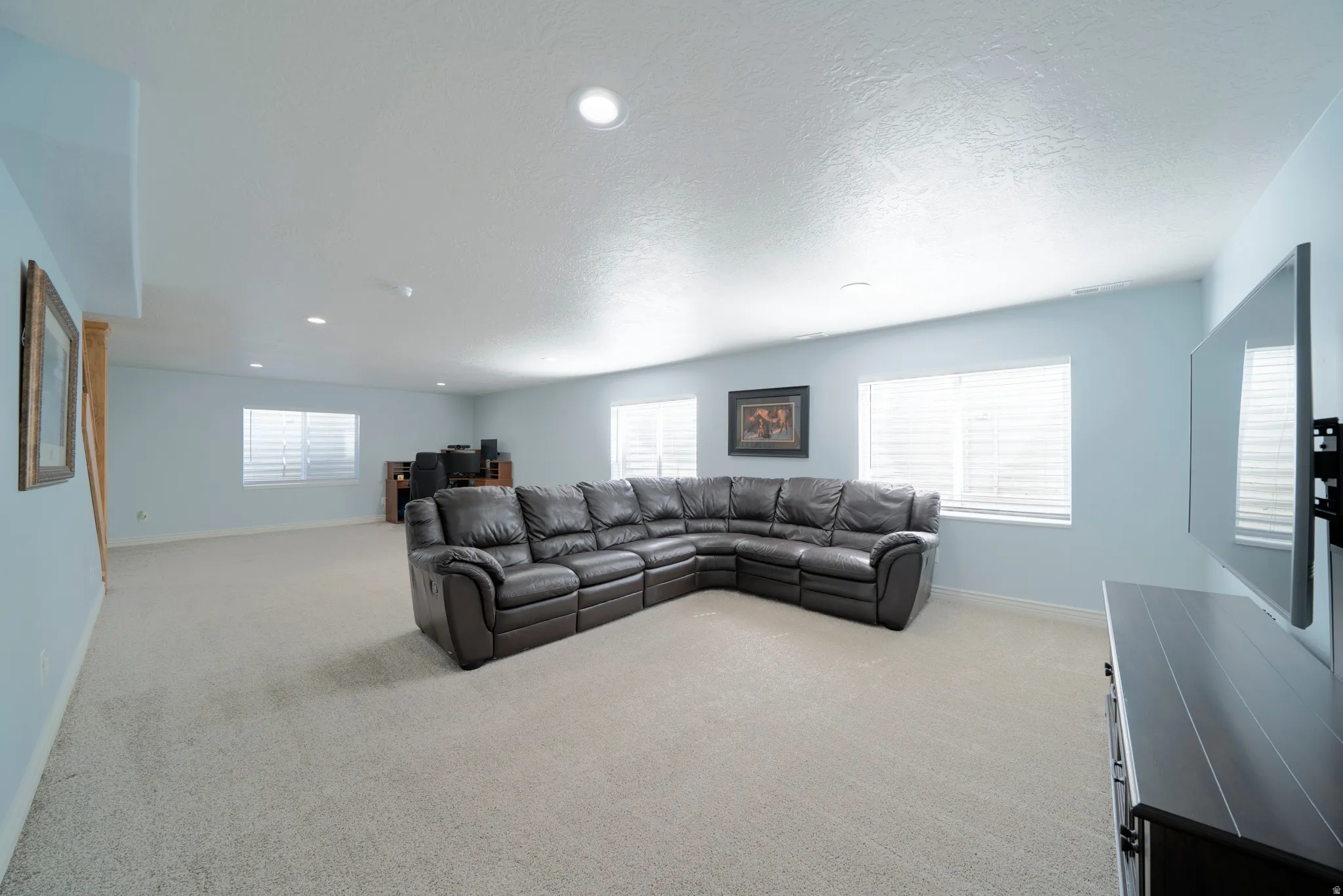 Living room with light colored carpet, a textured ceiling, and recessed lighting