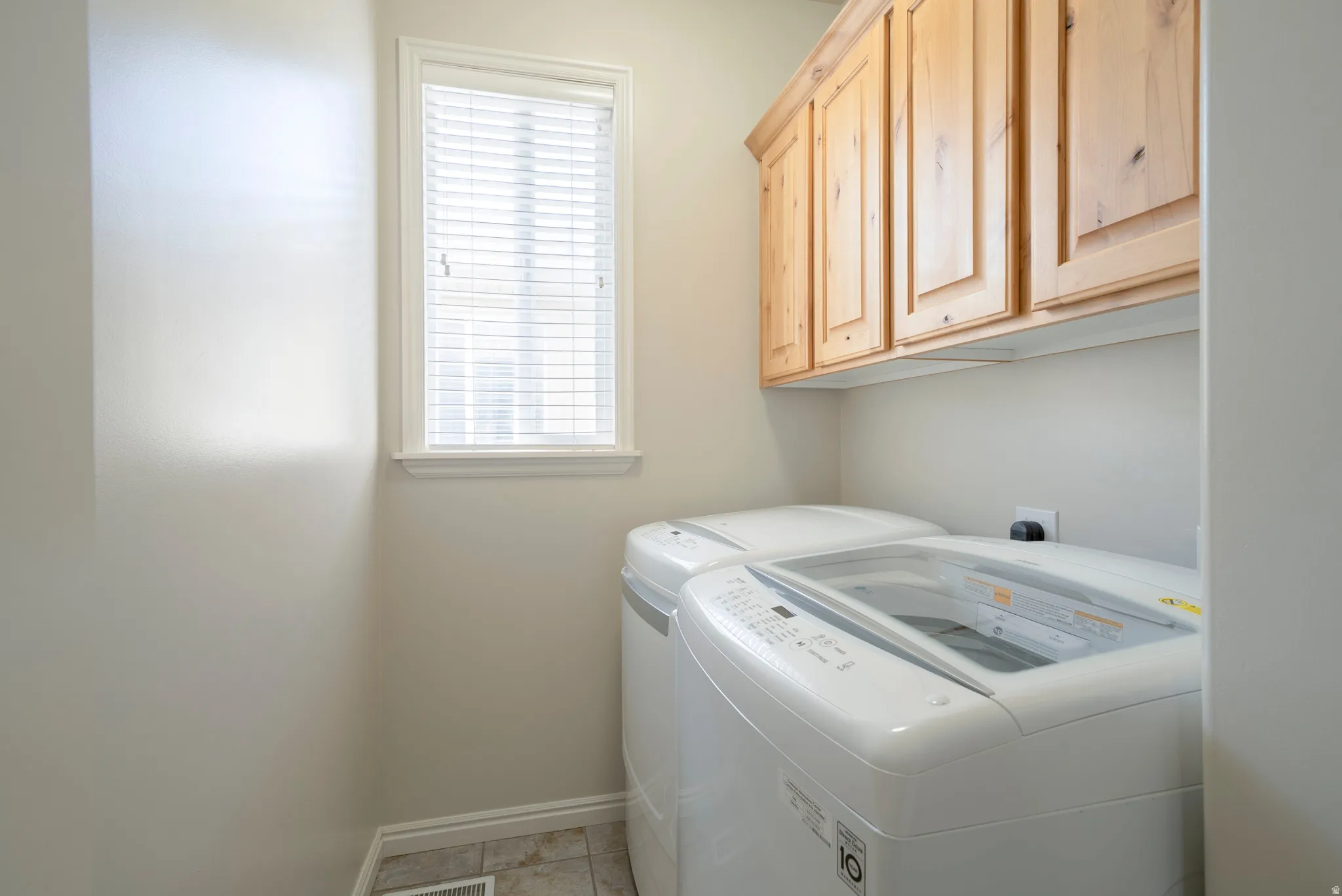 Laundry room with cabinet space, plenty of natural light, and washing machine and clothes dryer