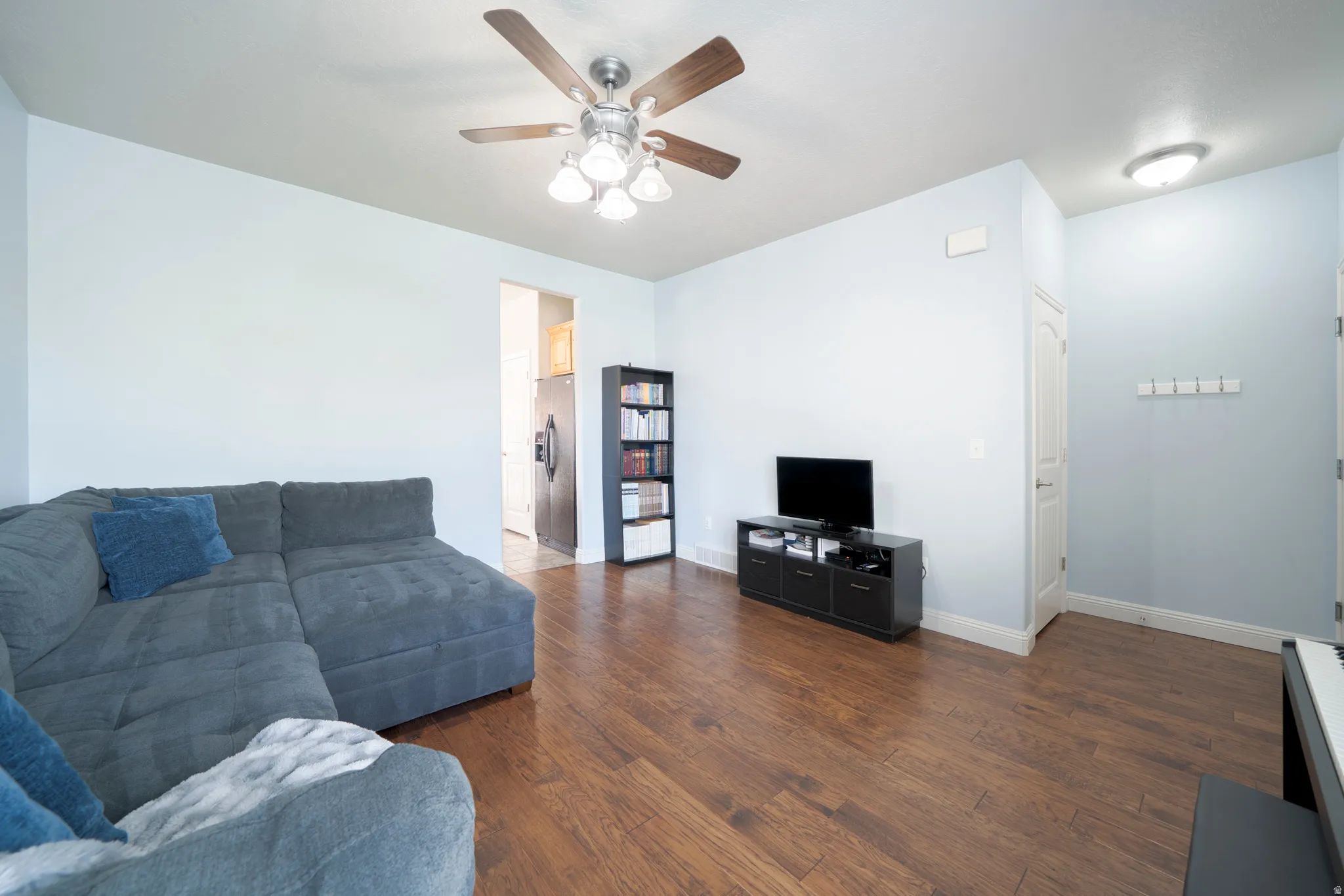 Living area featuring dark wood-style floors and a ceiling fan