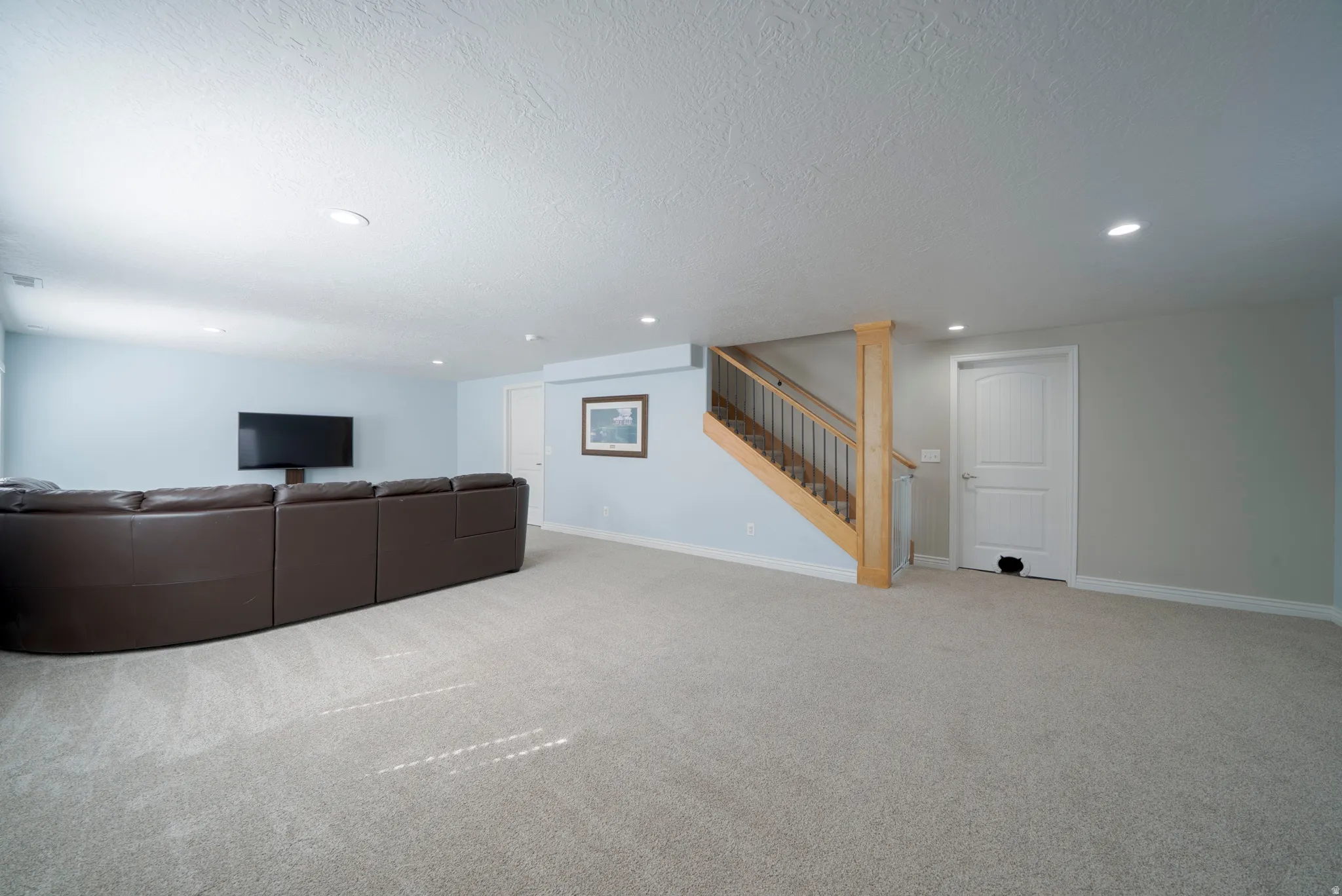 Unfurnished living room with light colored carpet, recessed lighting, and a textured ceiling