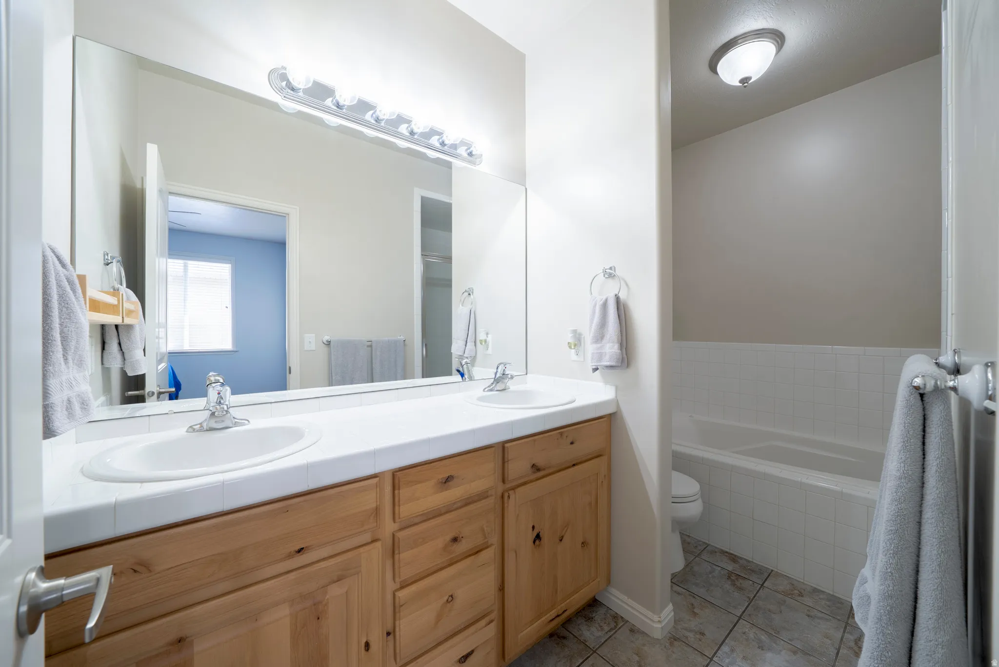 Bathroom featuring double vanity, a garden tub, and light tile patterned floors