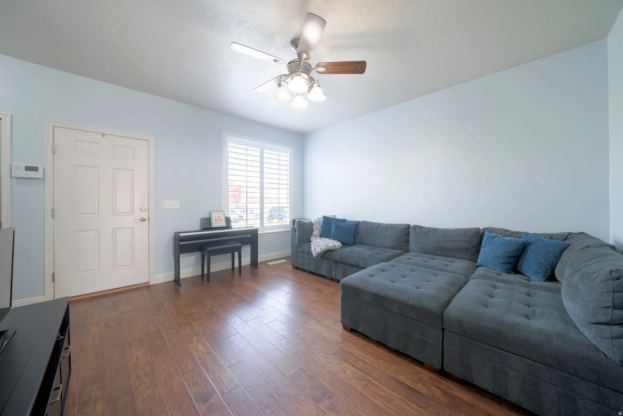 Living room featuring dark wood-style flooring and a ceiling fan