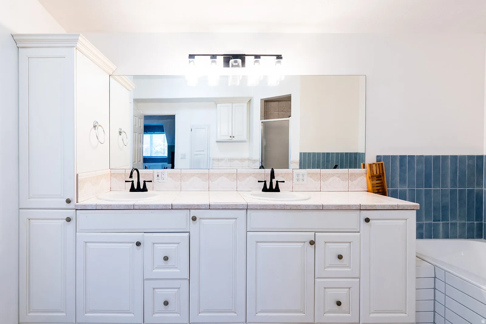 Full bathroom with double vanity, a shower stall, a garden tub, and tile walls