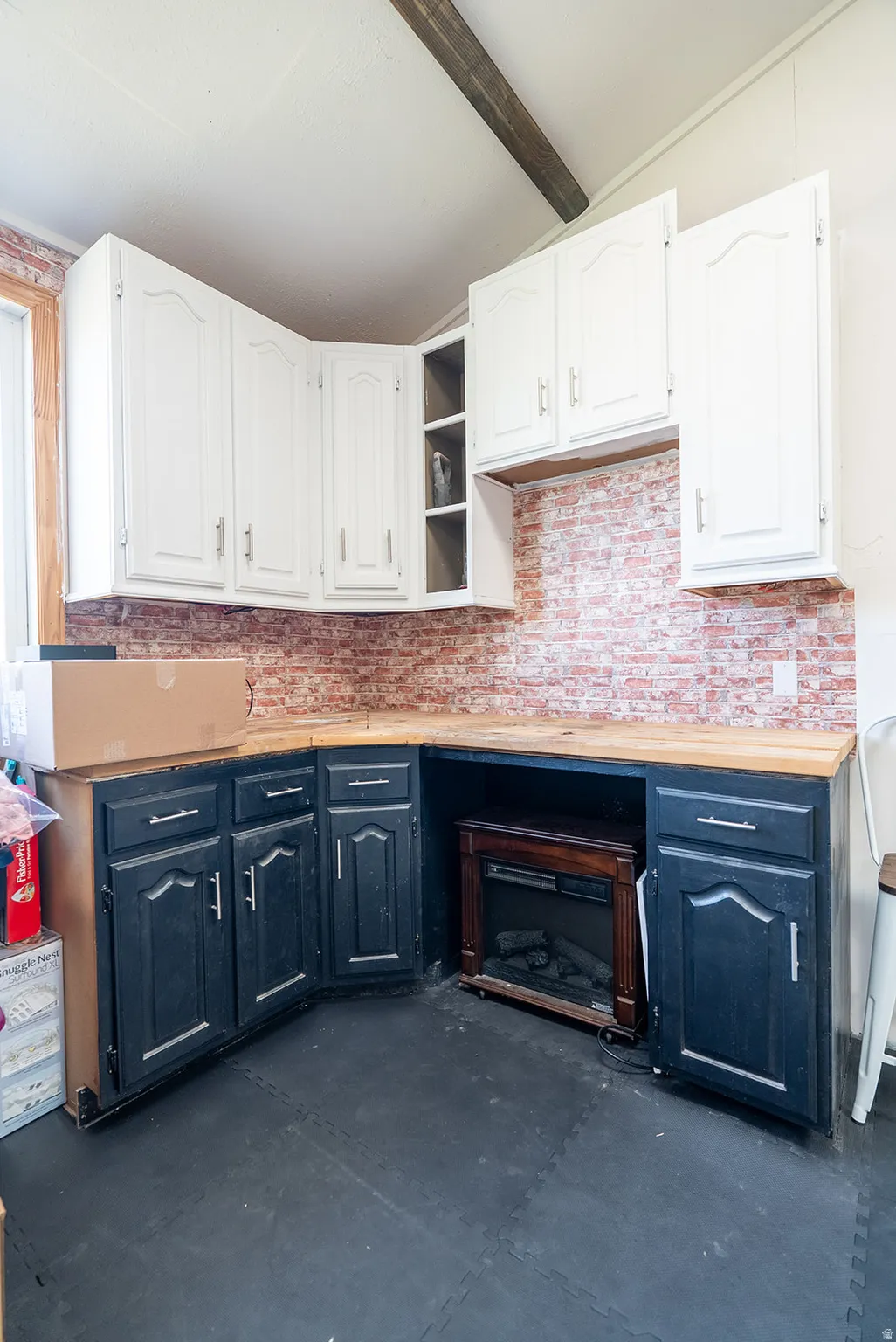 Kitchen with dual tone cabinets, concrete floors, vaulted ceiling with beams, open shelves, and butcher block counters