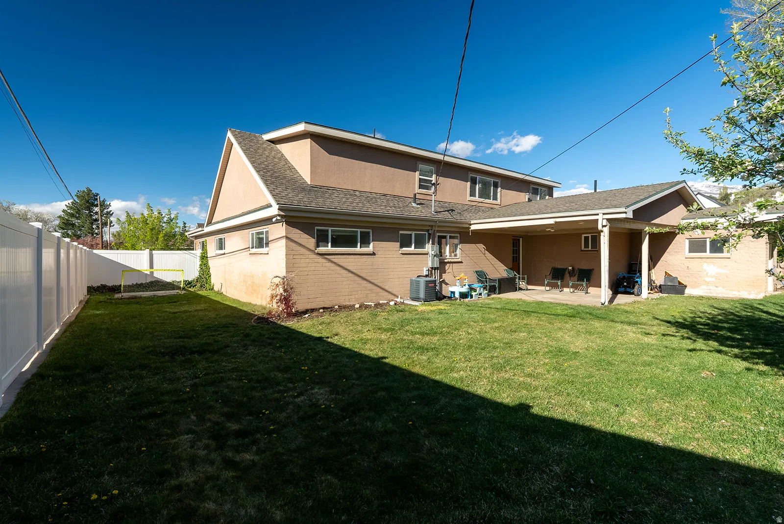 Rear view of property with a patio, a fenced backyard, a shingled roof, and brick siding