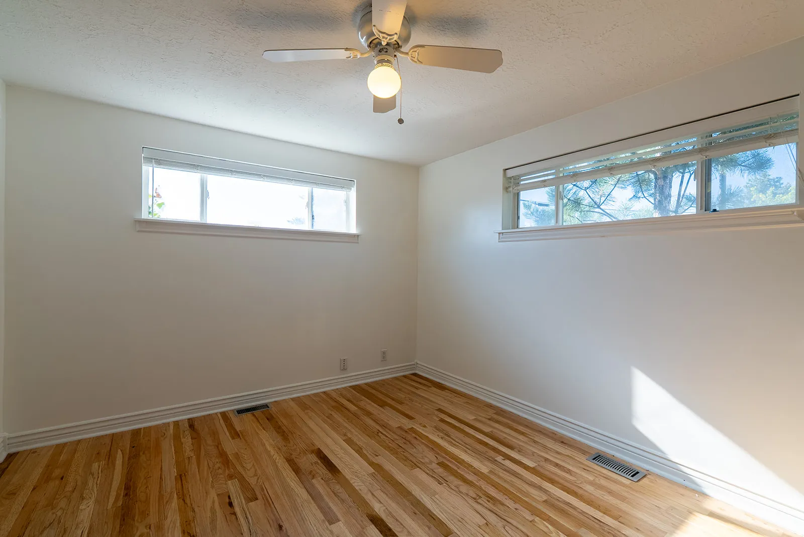 Unfurnished room with light wood-style flooring, plenty of natural light, ceiling fan, and a textured ceiling