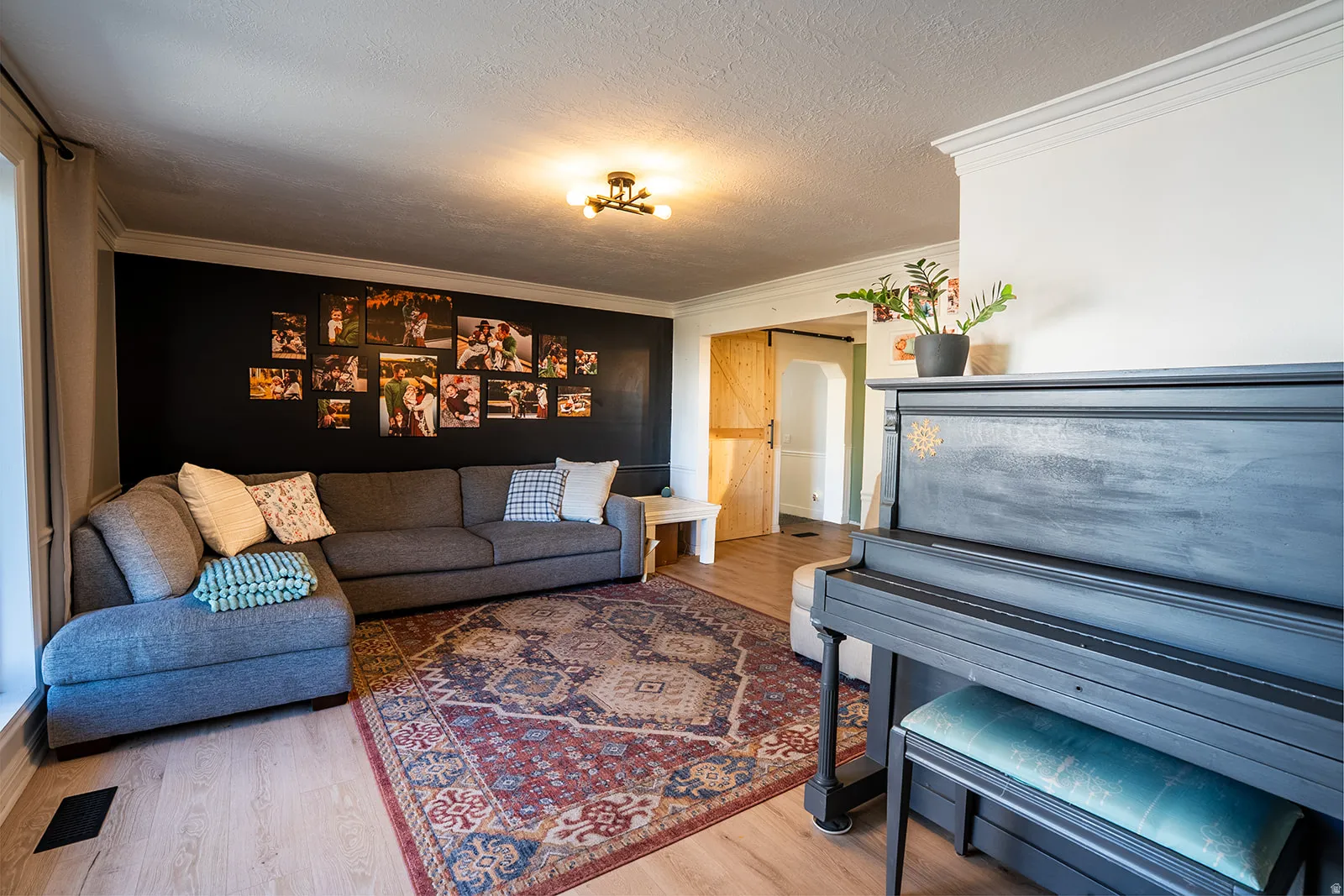 Living area featuring light wood finished floors, crown molding, and a textured ceiling
