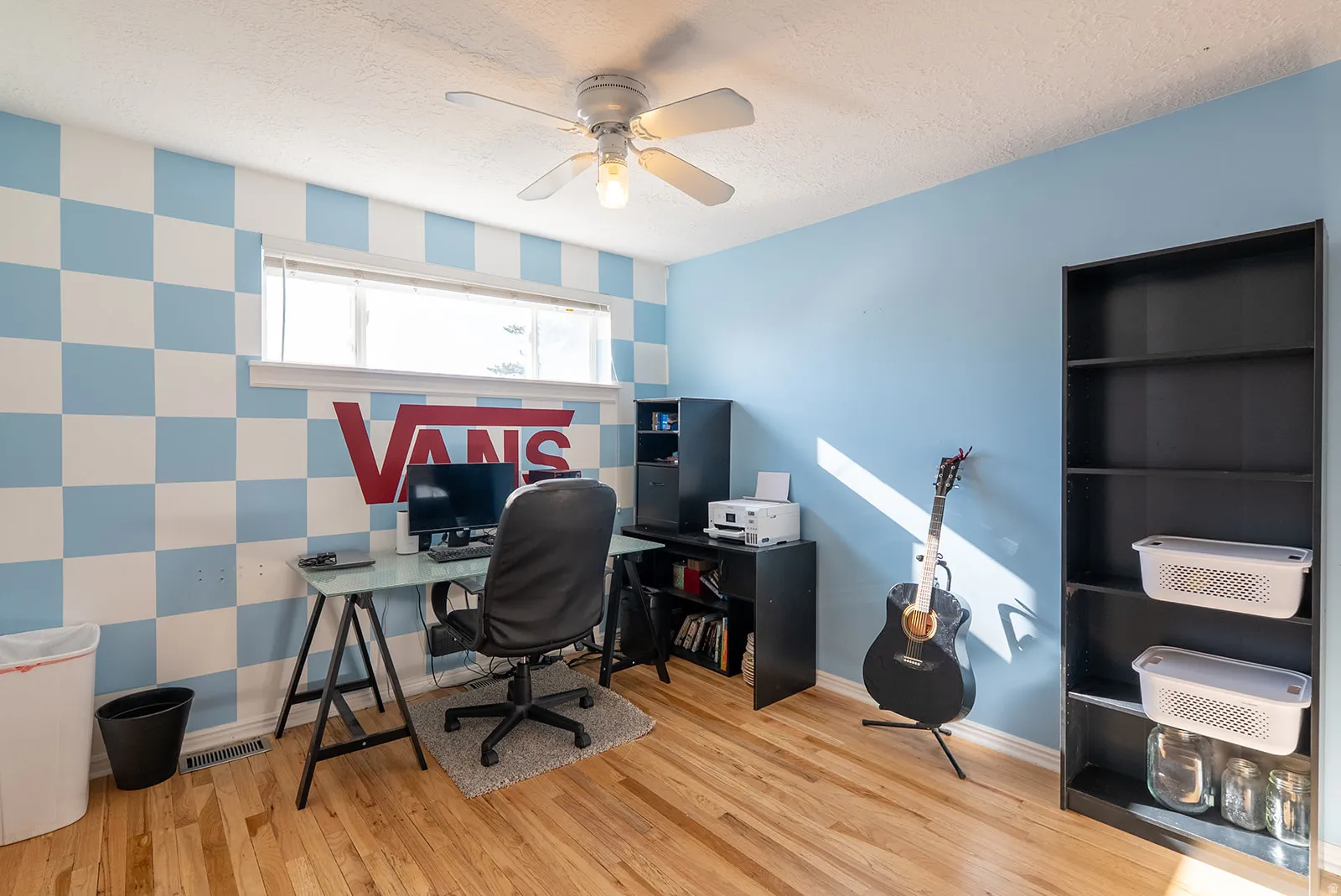 Home office with ceiling fan, light wood finished floors, wallpapered walls, an accent wall, and a textured ceiling