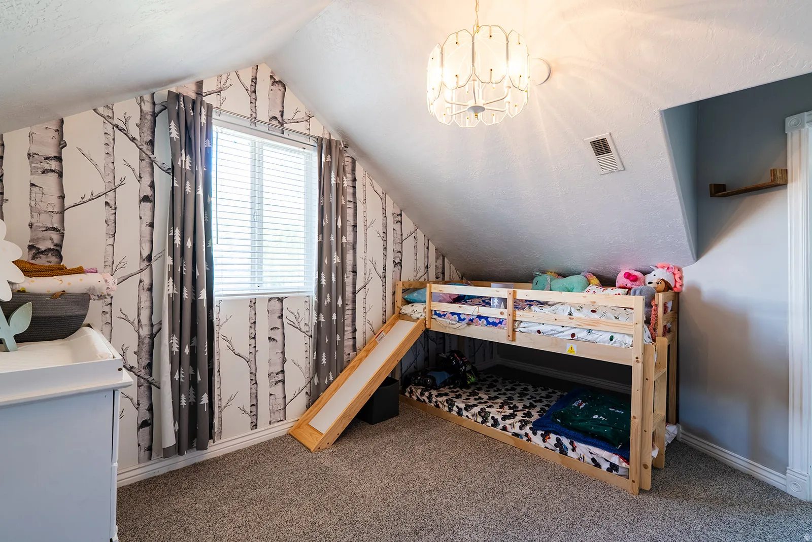 Carpeted bedroom with wallpapered walls and hanging lights