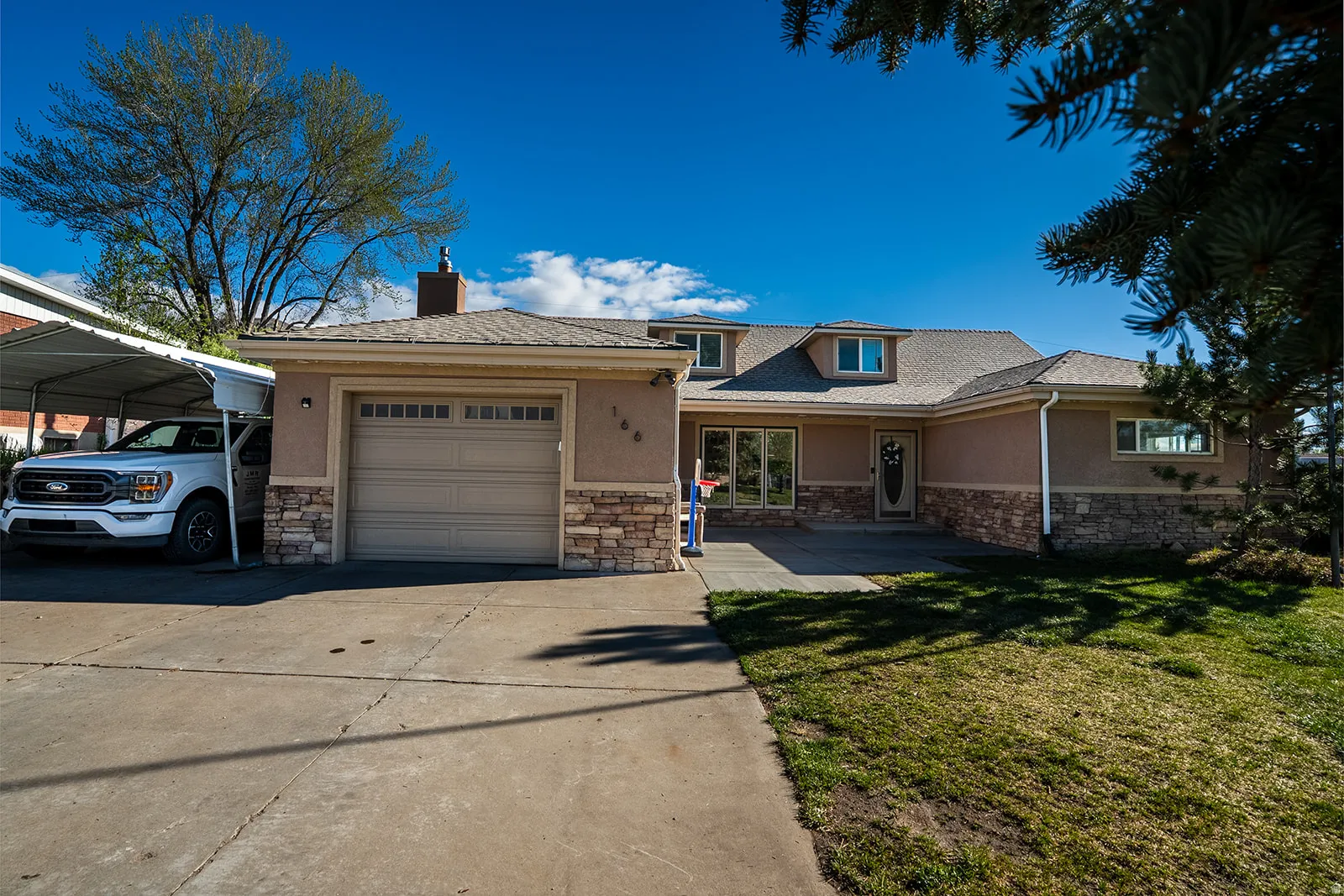 View of front of house featuring stucco siding, concrete driveway, an attached garage, and a chimney