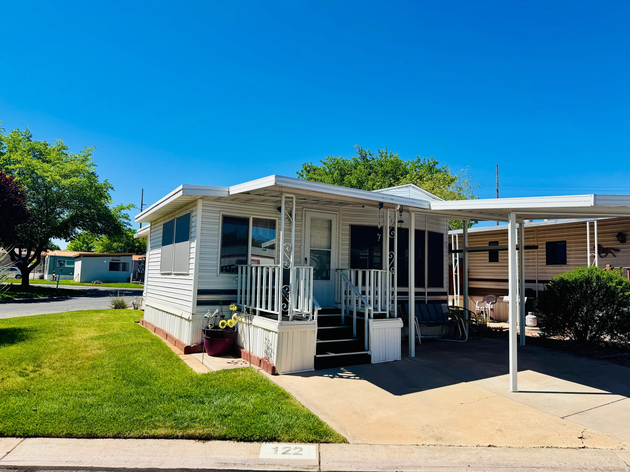 Manufactured / mobile home with a front lawn, a carport, and concrete driveway
