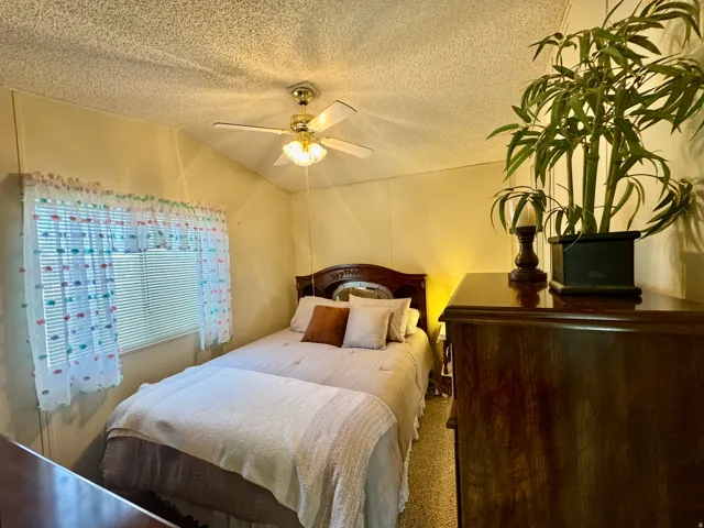 Bedroom featuring a textured ceiling, ceiling fan, and carpet floors