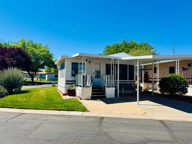 Manufactured / mobile home with a front yard, a carport, and concrete driveway