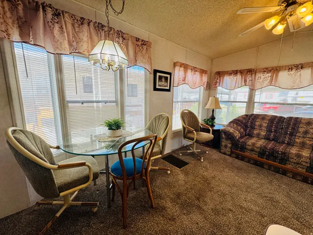 Carpeted dining space with a ceiling fan and hanging lights