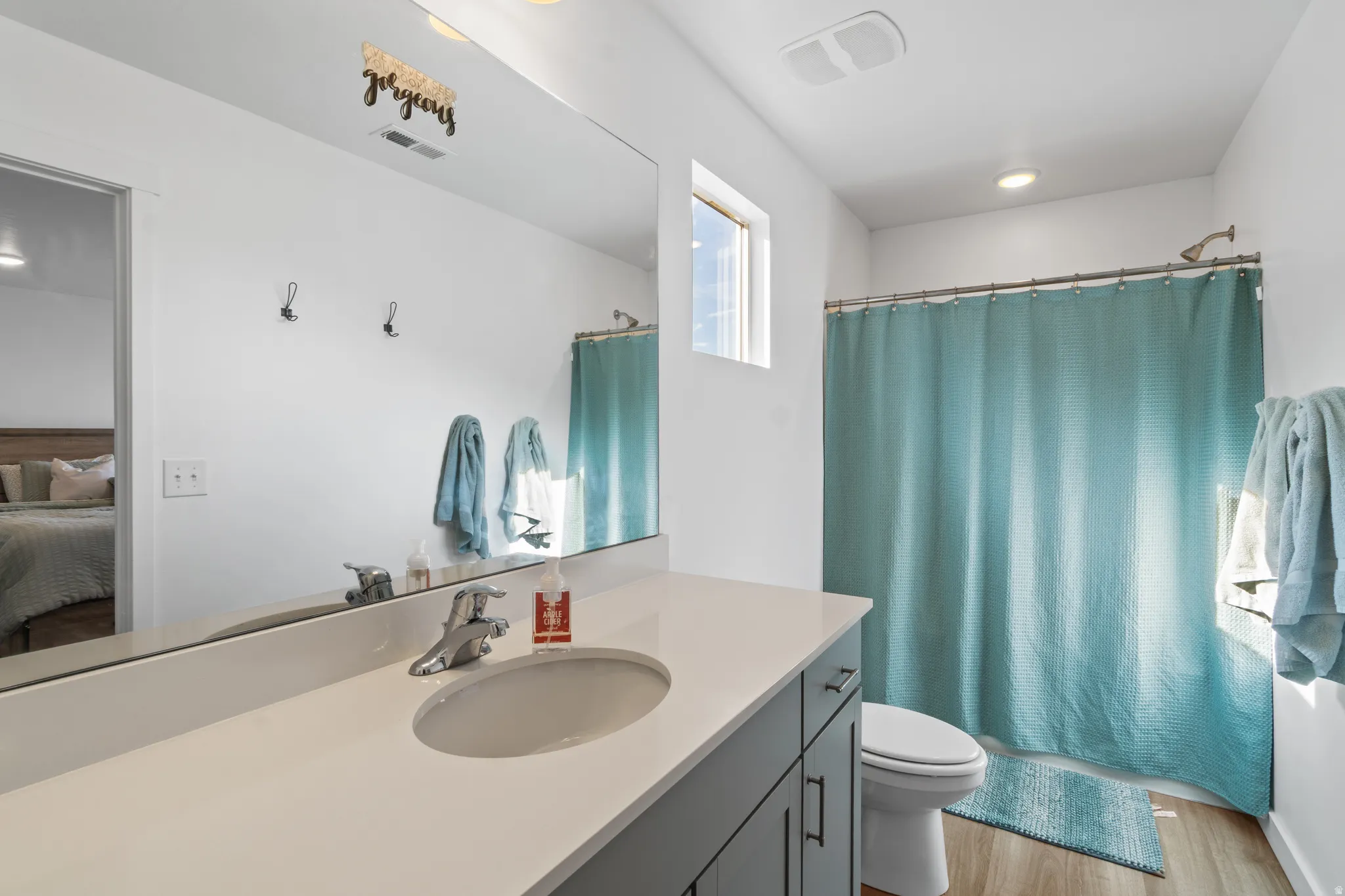 Bathroom with vanity, shower / tub combo with curtain, light wood finished floors, and ensuite bath