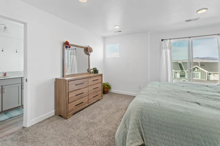 Bedroom featuring light carpet and multiple windows