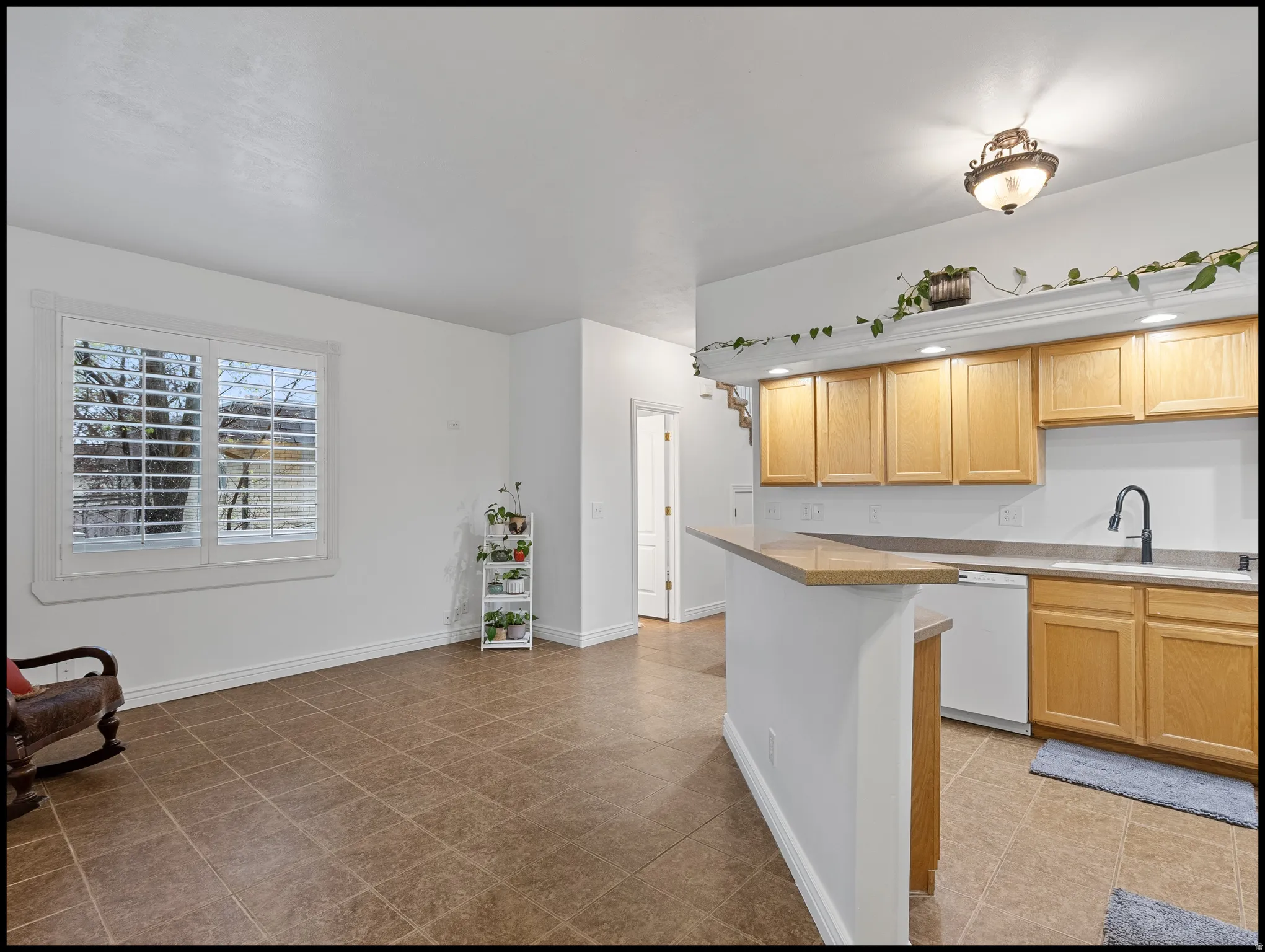 Kitchen with light countertops, light wood finish cabinetry, dishwasher, and a breakfast bar area