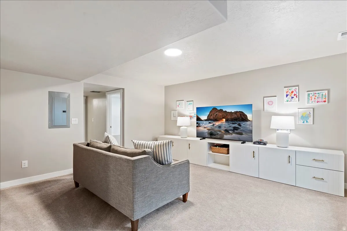 Living room with electric panel and light colored carpet