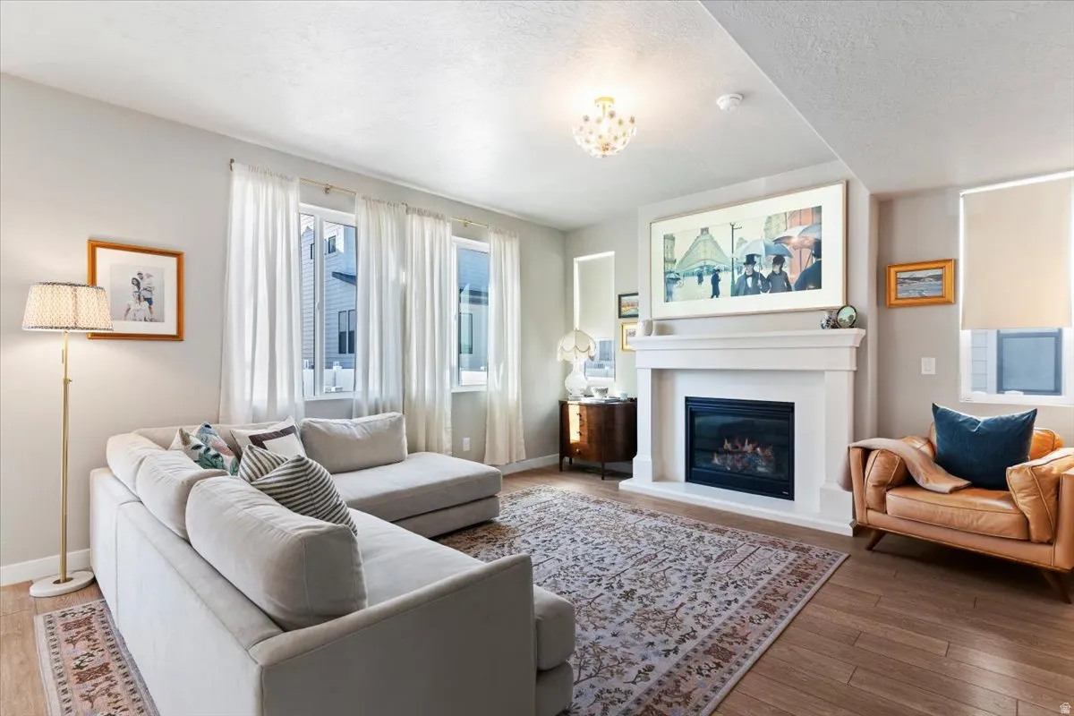 Living room with hardwood / wood-style flooring, a glass covered fireplace, and a textured ceiling
