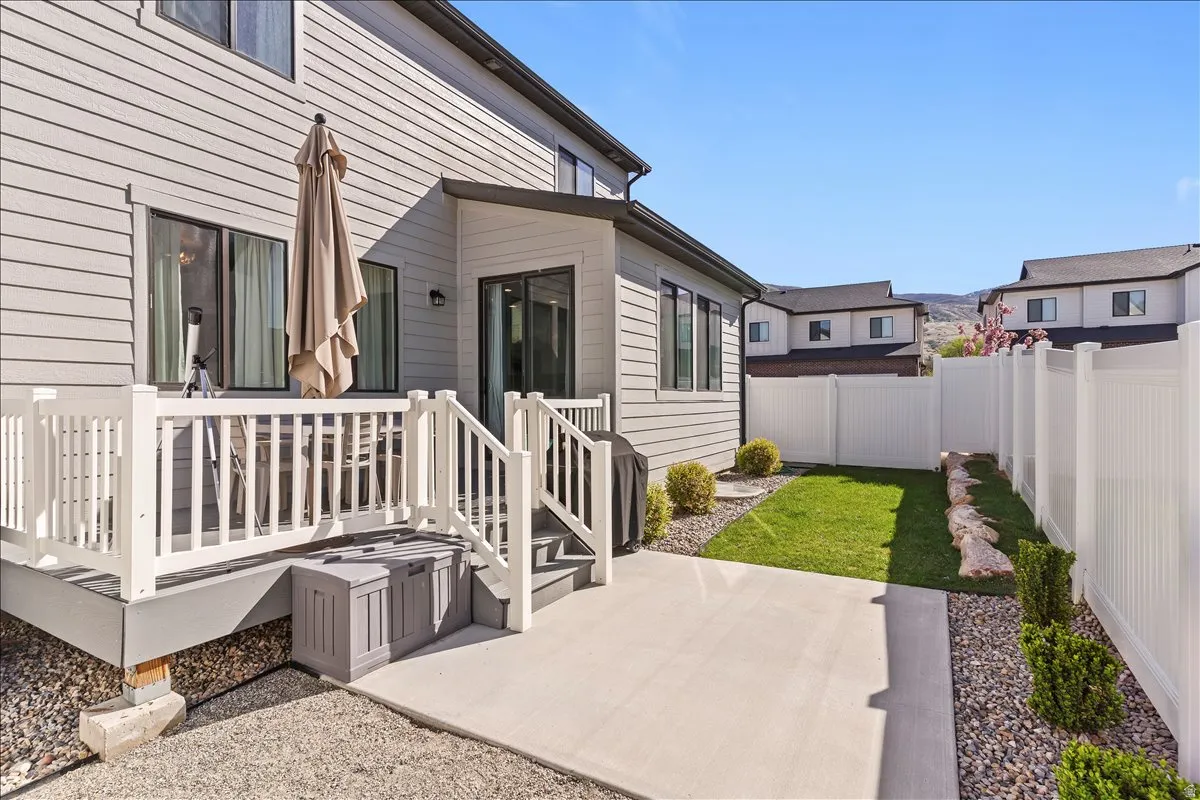 Fenced backyard featuring a wooden deck and a patio