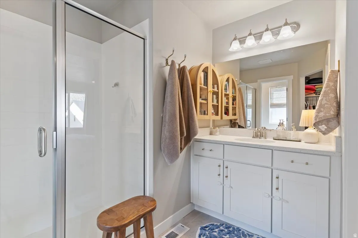 Bathroom featuring vanity, a stall shower, and light tile patterned floors