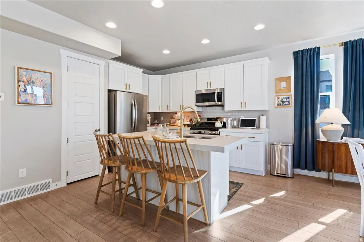 Kitchen with white cabinetry, a center island with sink, stainless steel appliances, and recessed lighting