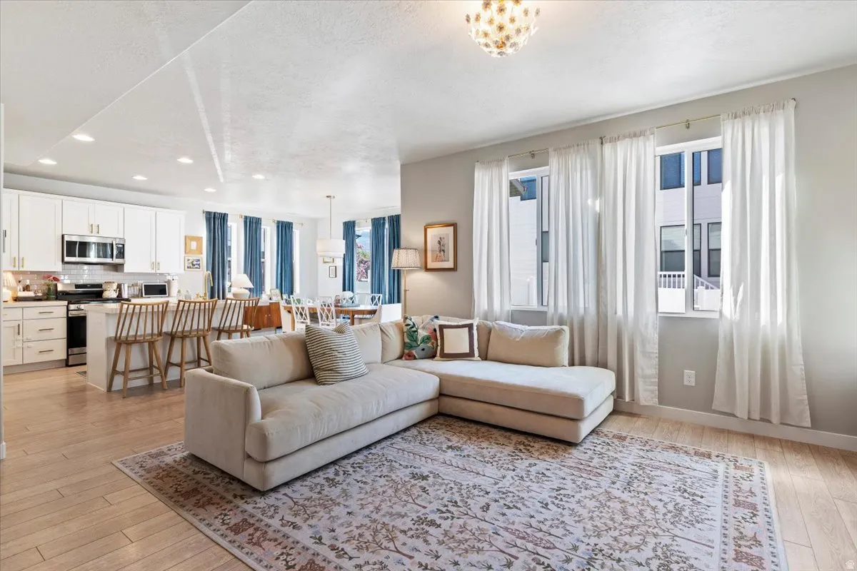Living room featuring light wood-type flooring, a textured ceiling, and recessed lighting
