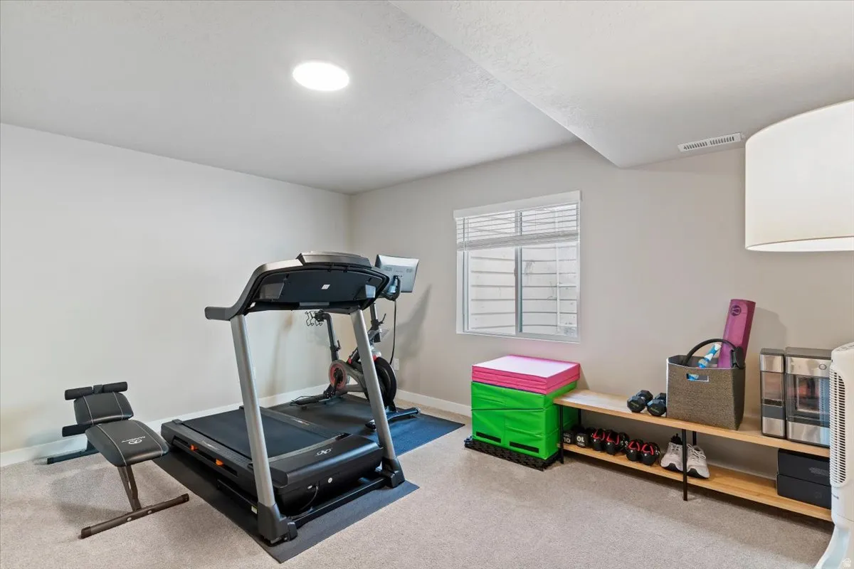 Exercise area featuring light colored carpet and baseboards
