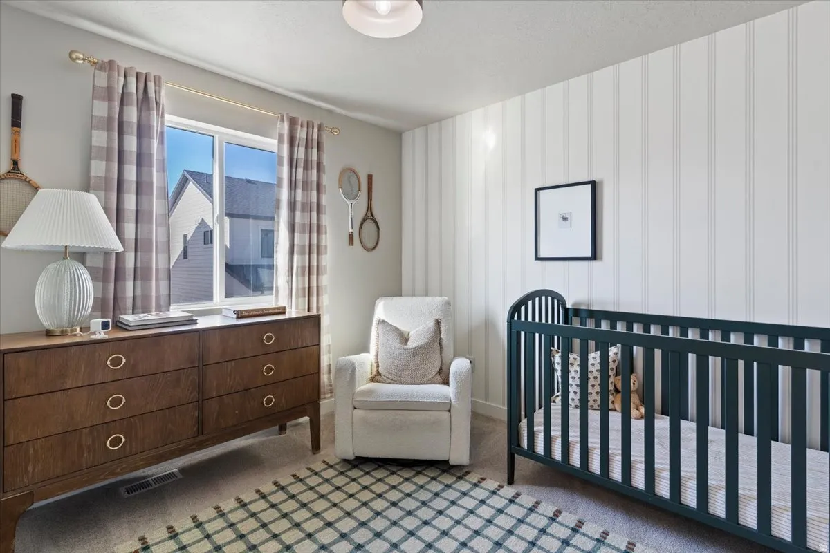 Bedroom featuring a nursery area and carpet flooring