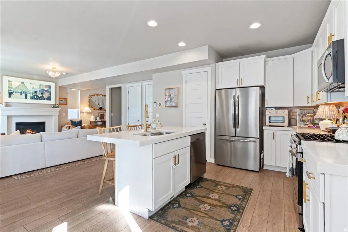 Kitchen with white cabinets, stainless steel appliances, open floor plan, a breakfast bar, and light wood finished floors