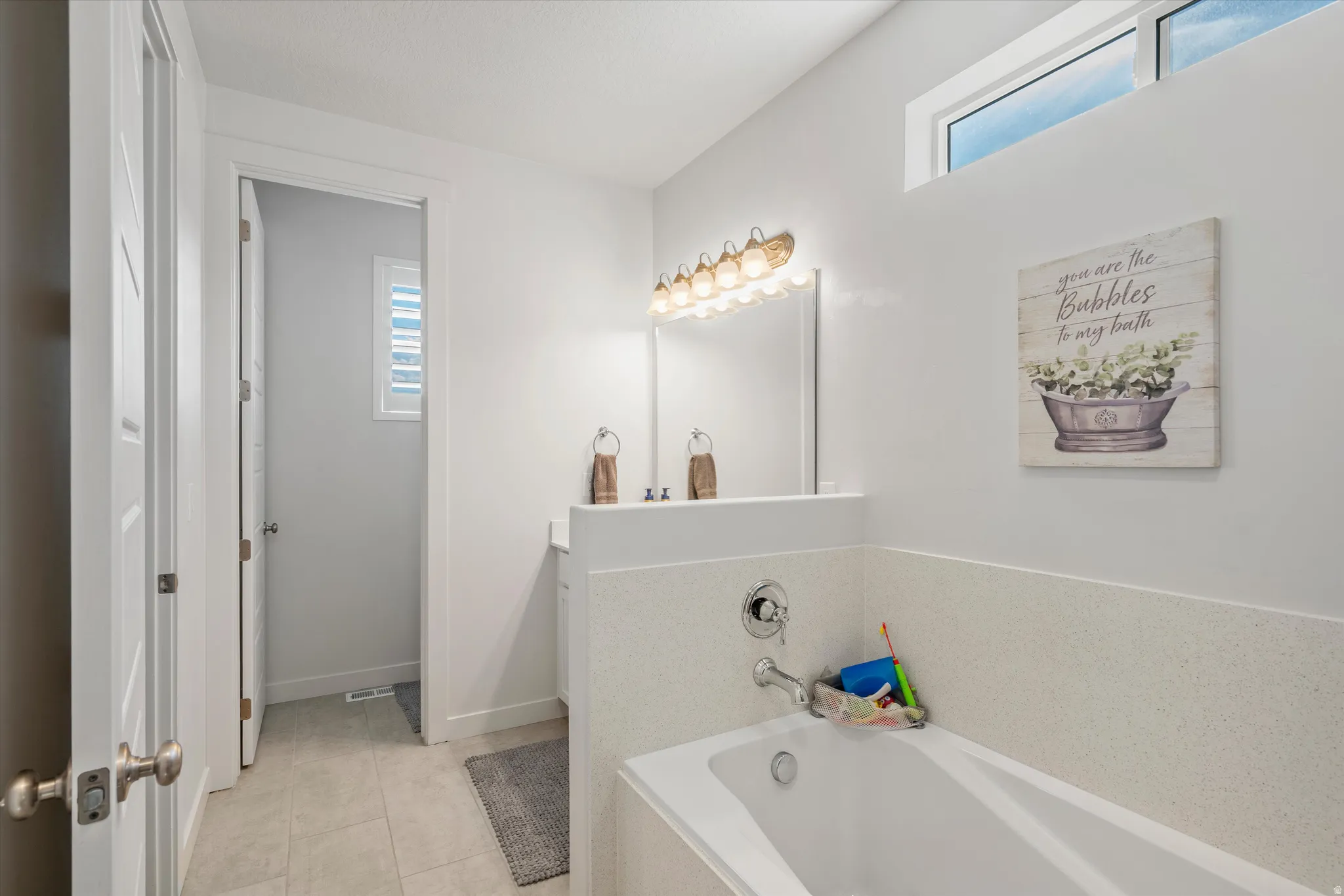 Full bathroom with a garden tub, vanity, and light tile patterned floors