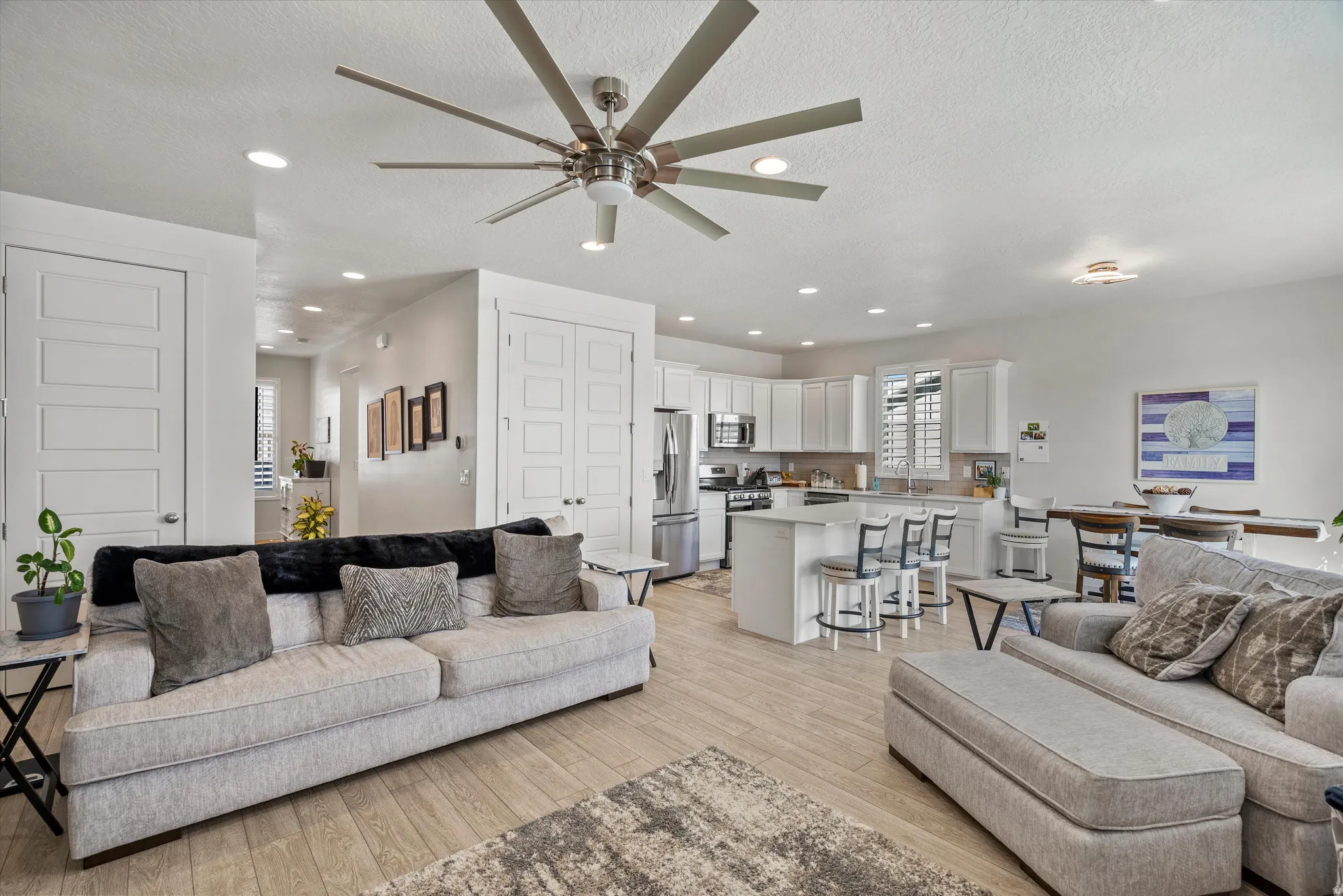 Living area with ceiling fan, light wood finished floors, a textured ceiling, and recessed lighting