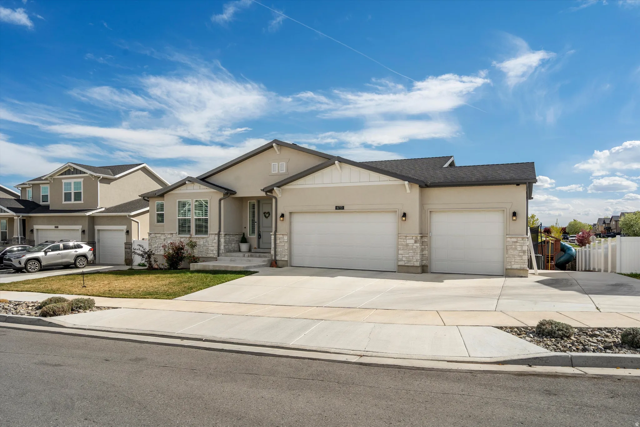 View of front facade featuring a garage, stone siding, and concrete driveway