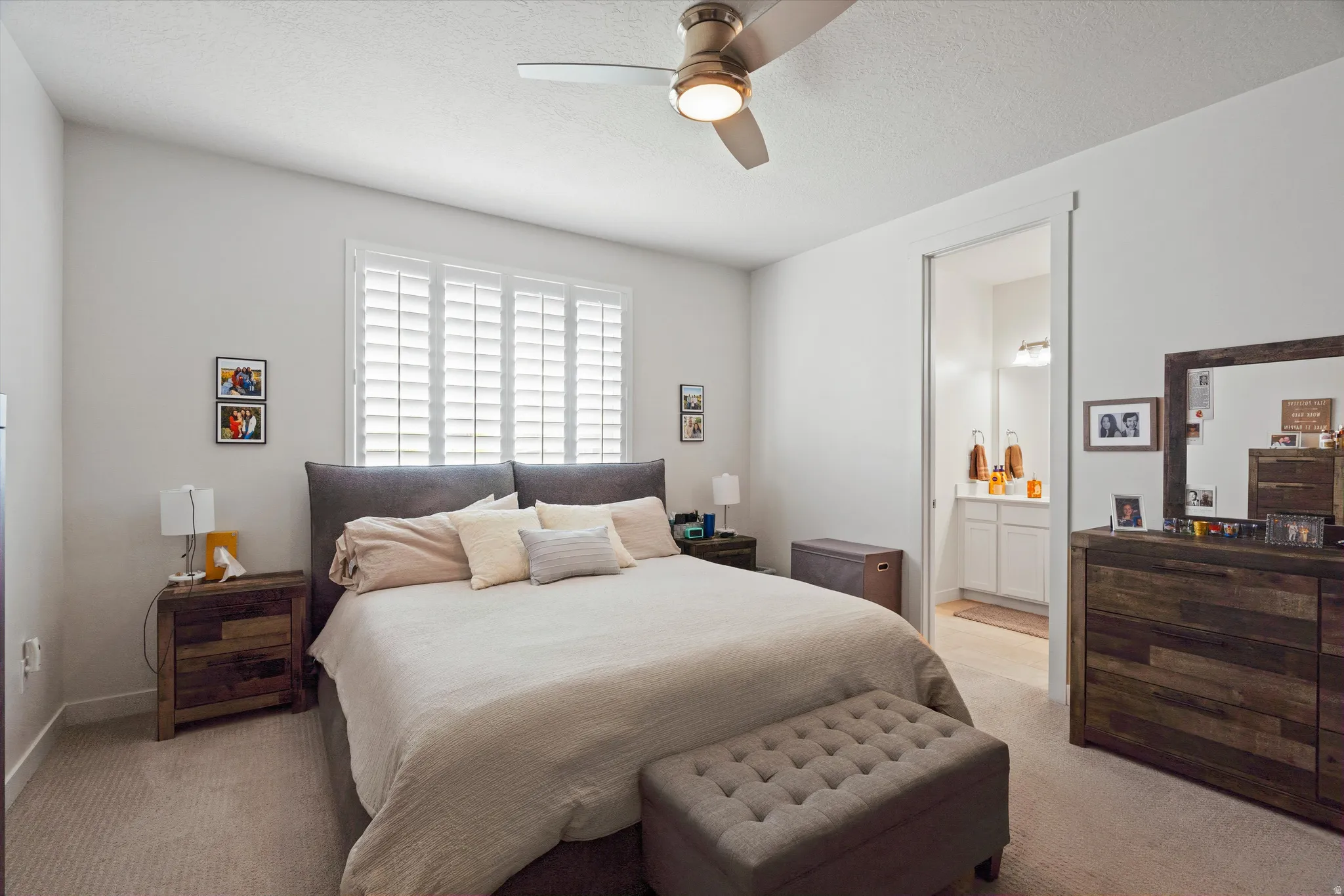 Bedroom with ceiling fan, light carpet, and a textured ceiling