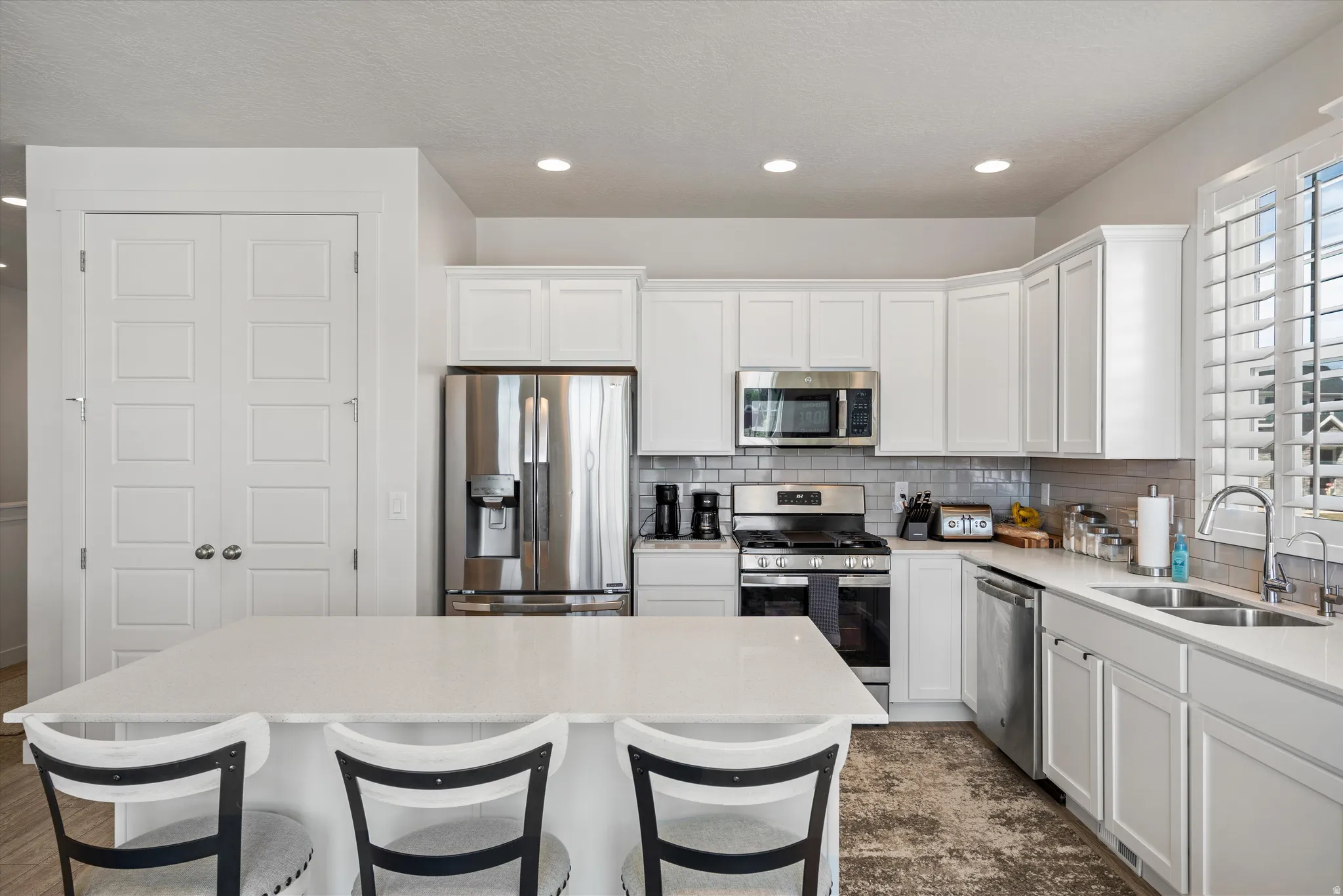 Kitchen with stainless steel appliances, a breakfast bar, a center island, white cabinetry, and recessed lighting