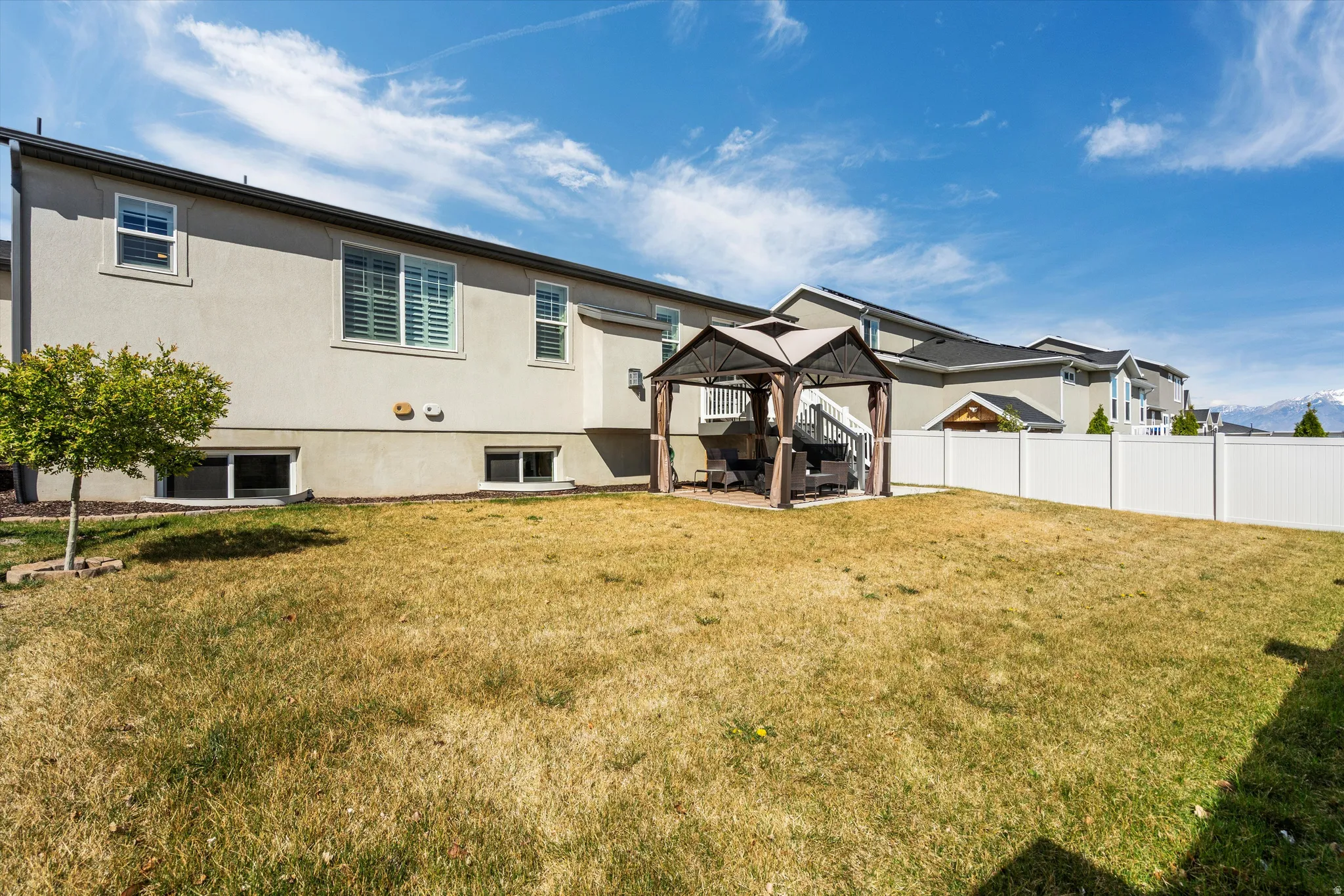 Rear view of property featuring a patio area, a gazebo, a fenced backyard, and stucco siding