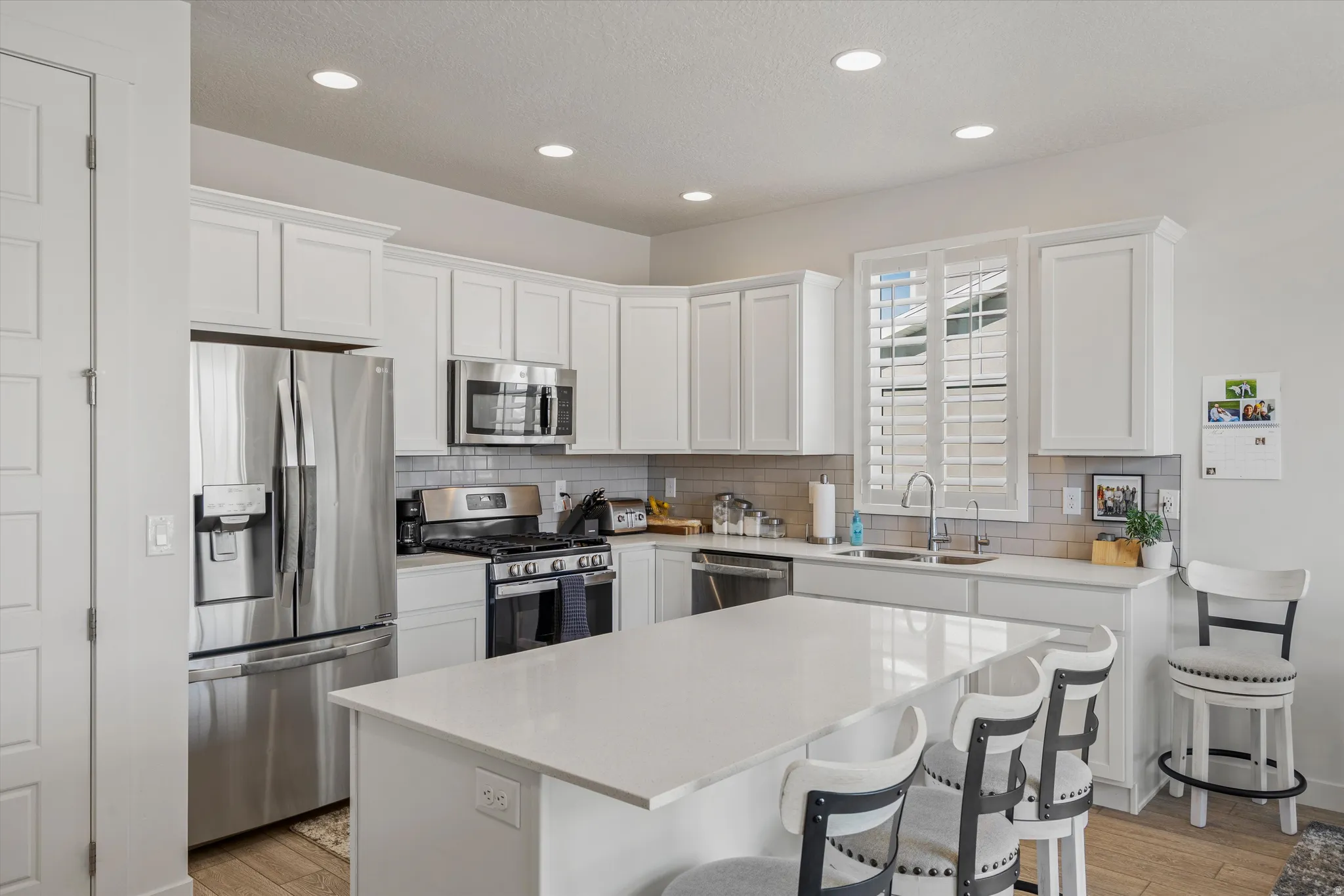 Kitchen with stainless steel appliances, white cabinets, and recessed lighting