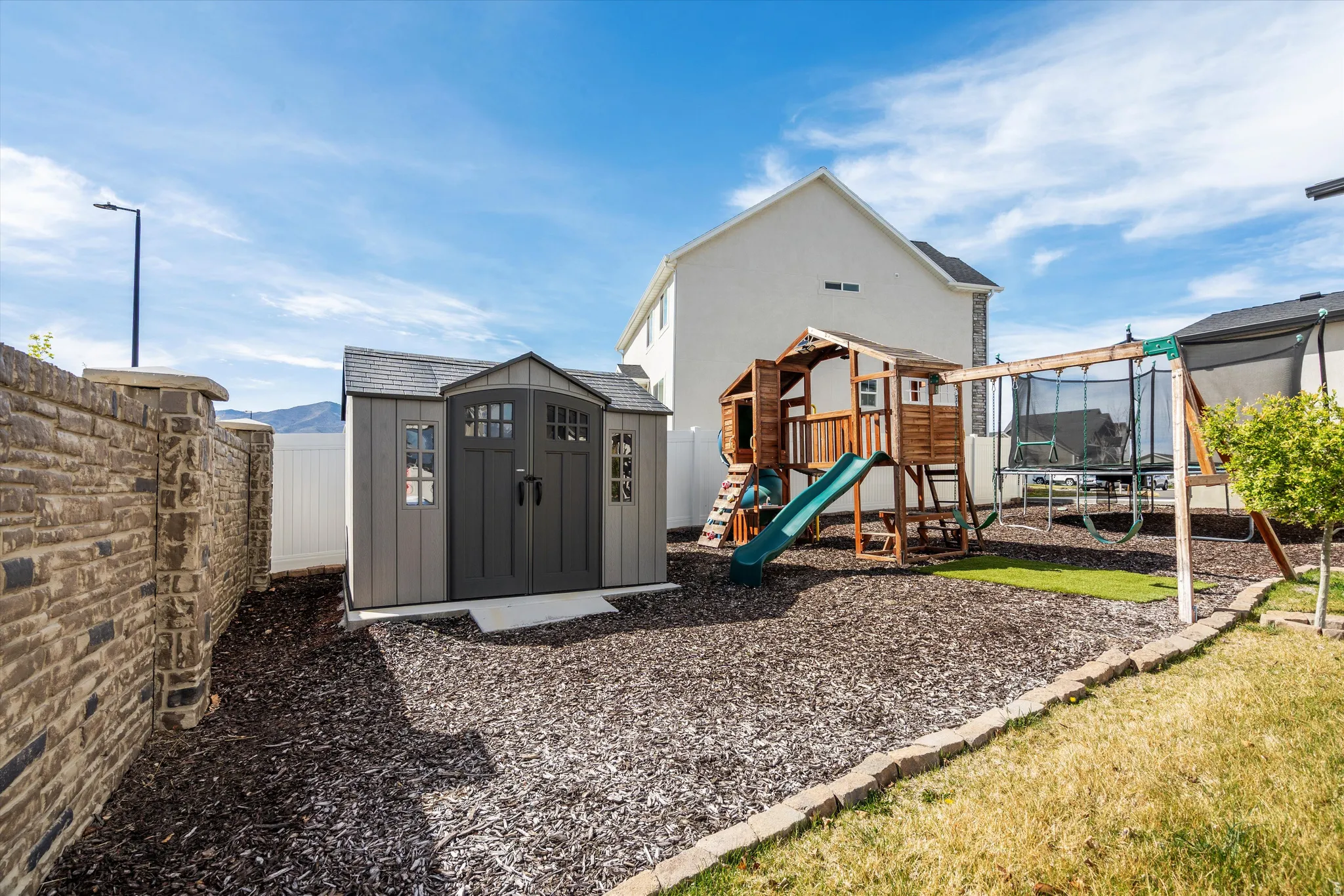 View of play area featuring a storage shed, a fenced backyard, and a trampoline