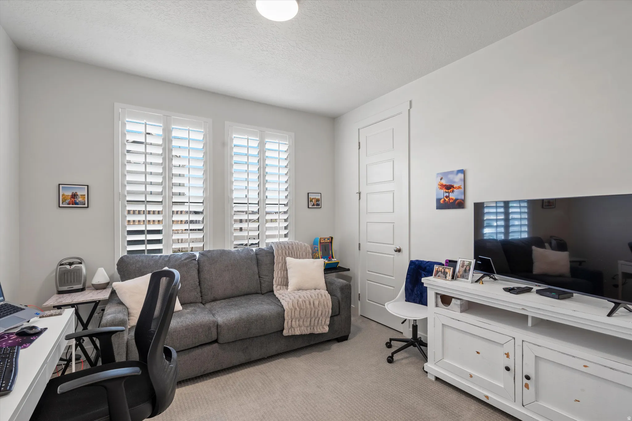 Home office with light carpet and a textured ceiling