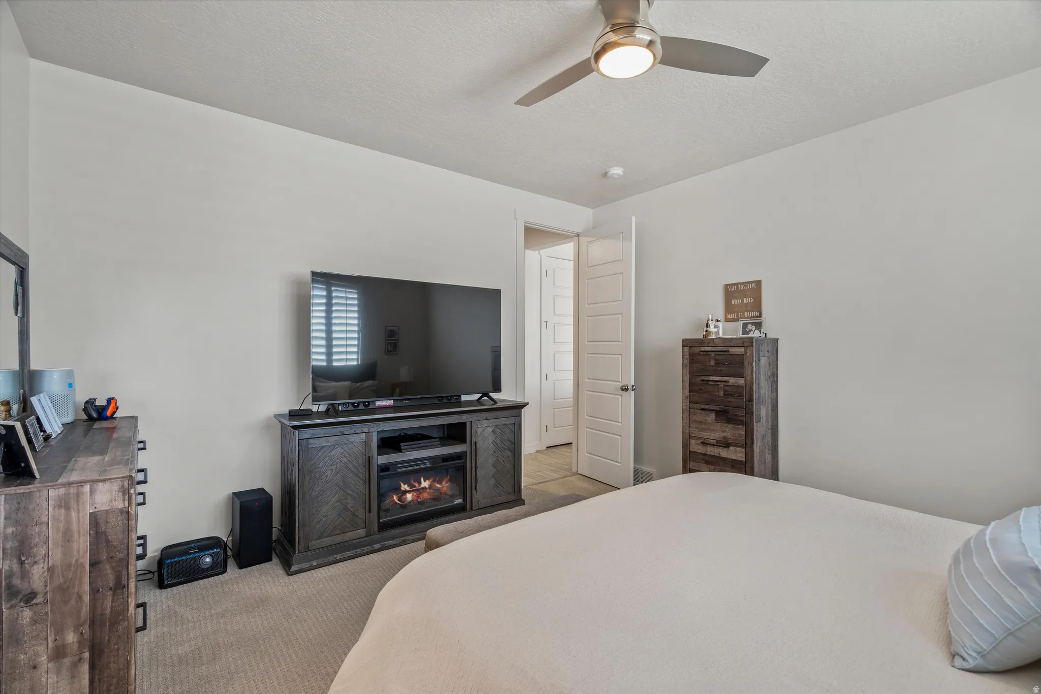 Bedroom featuring carpet, ceiling fan, a textured ceiling, and a fireplace