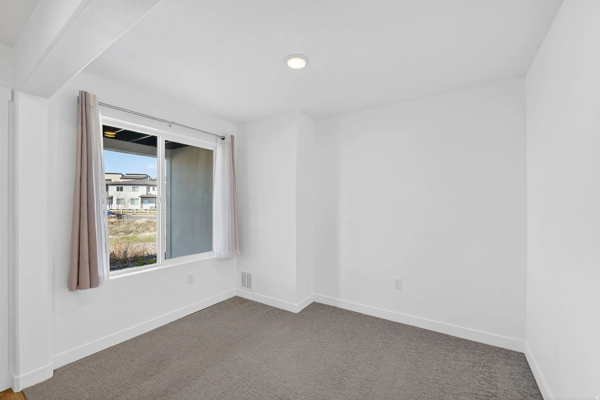 Spare room featuring baseboards and dark carpet