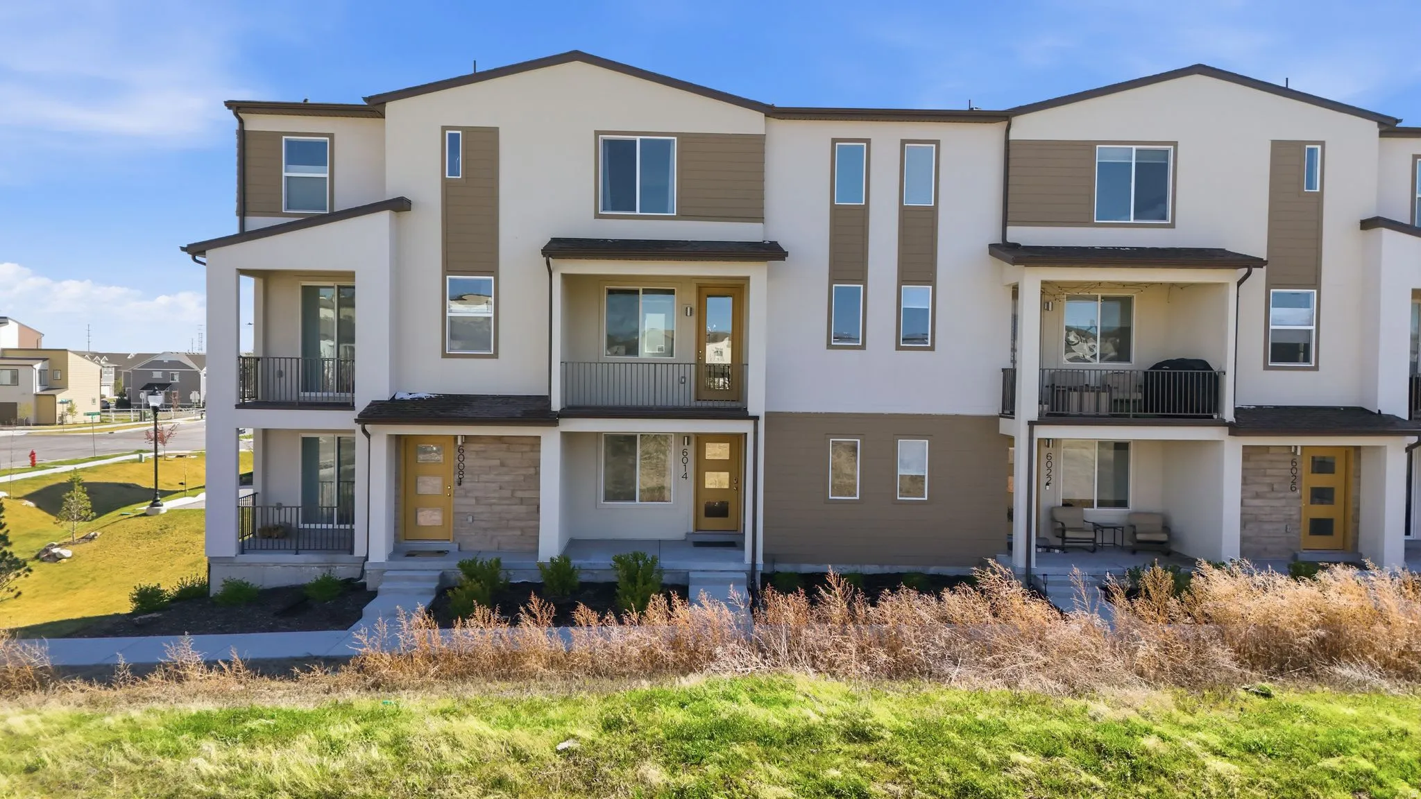 View of front of house featuring a balcony, stone siding, stucco siding, and a residential view