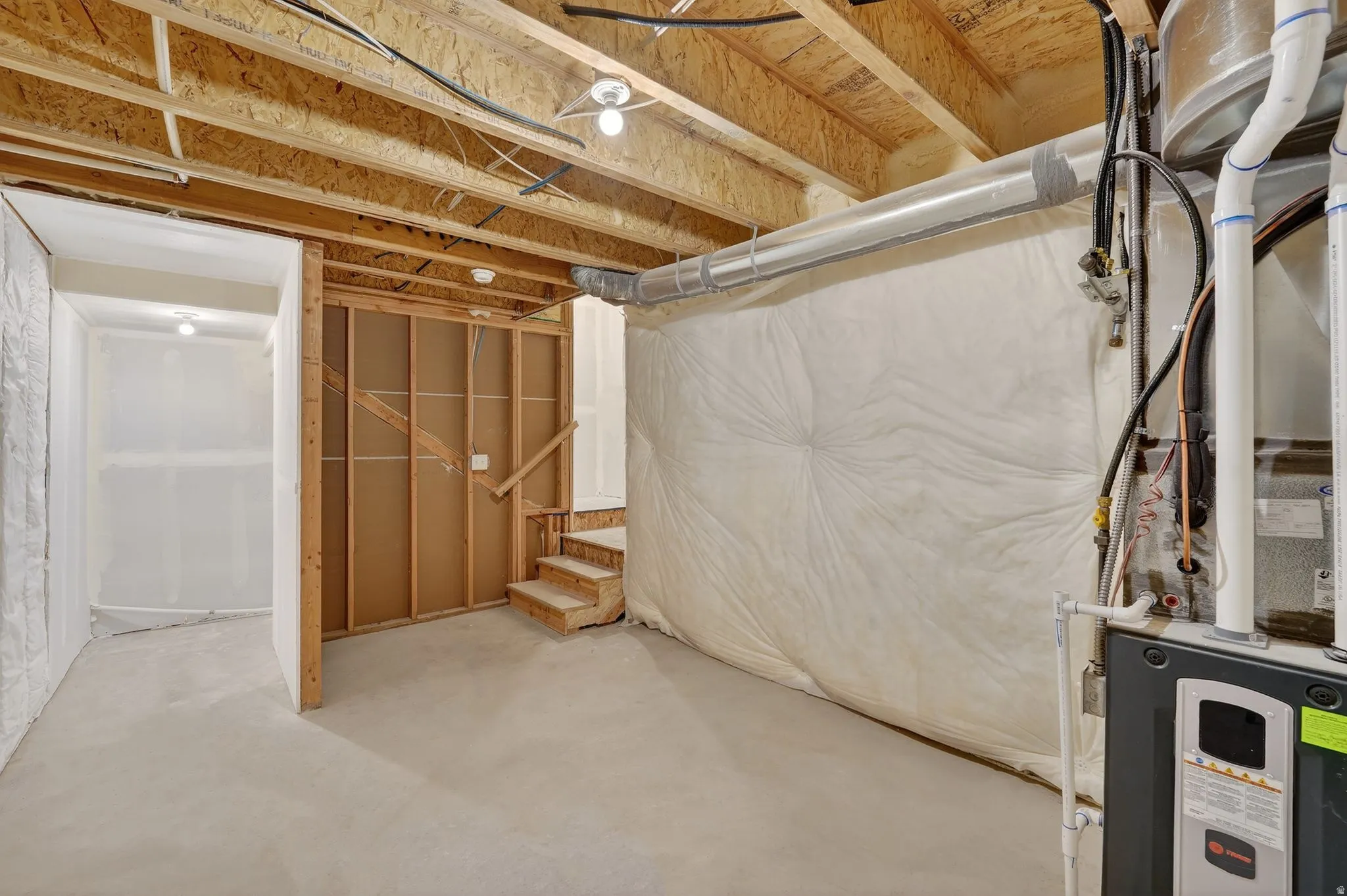 Unfinished basement with stairs and heating unit
