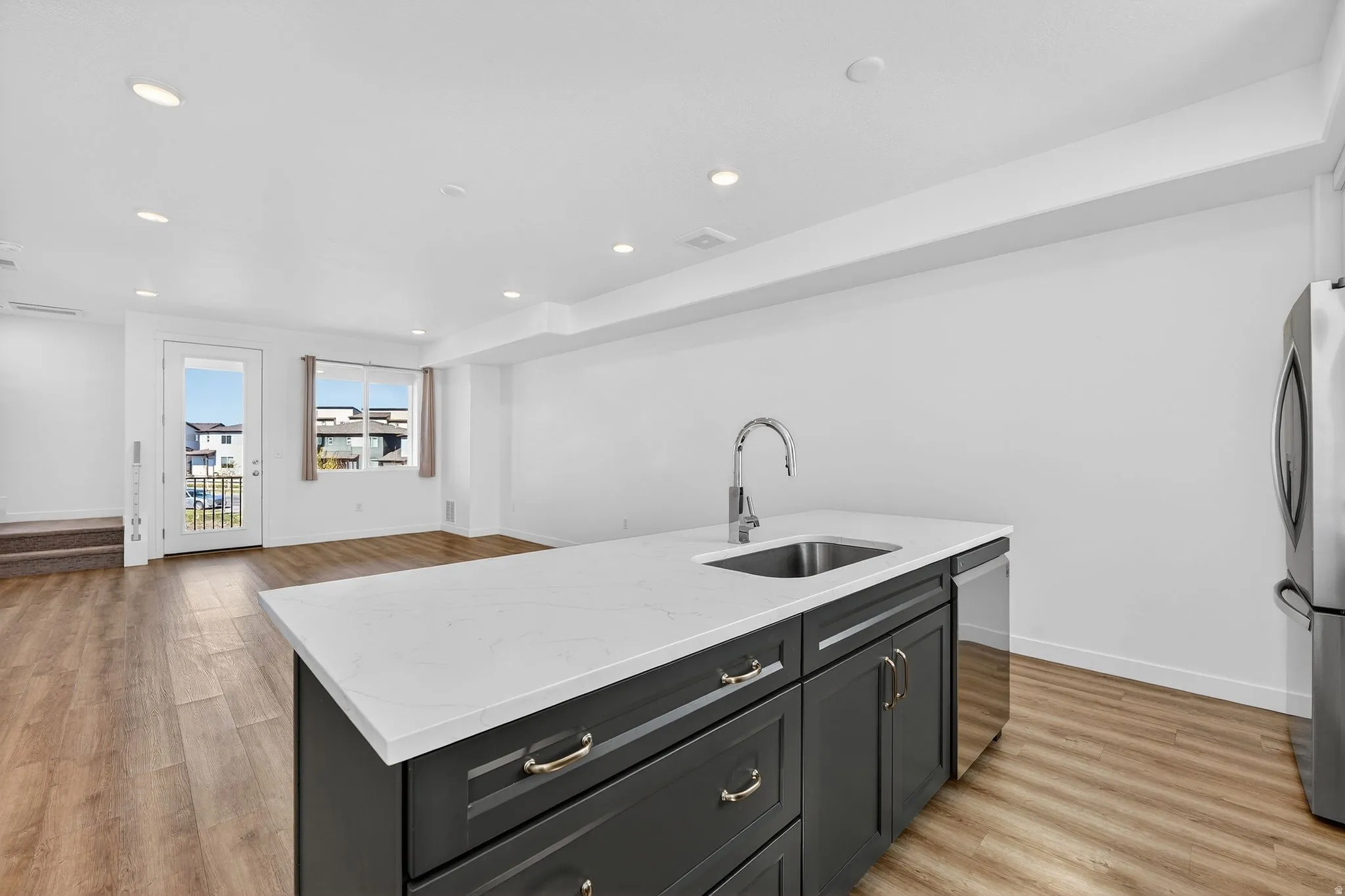 Kitchen featuring a kitchen island with sink, recessed lighting, light stone countertops, light wood-style floors, and stainless steel appliances
