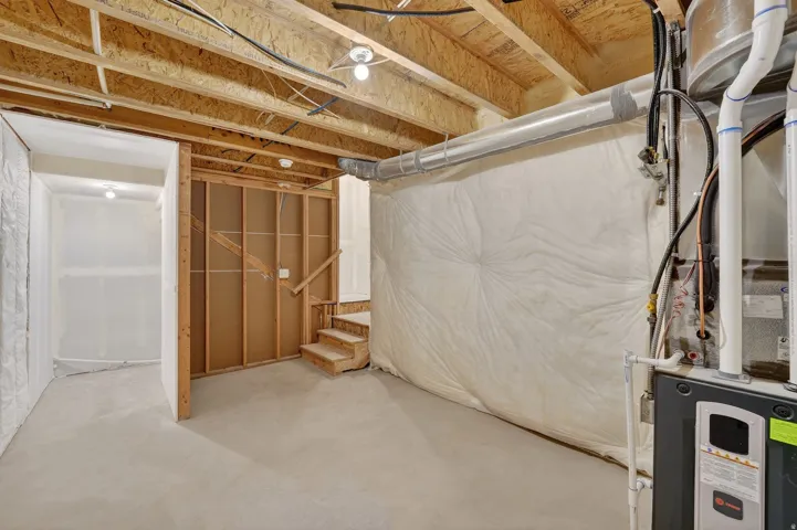Unfinished basement with stairs and heating unit