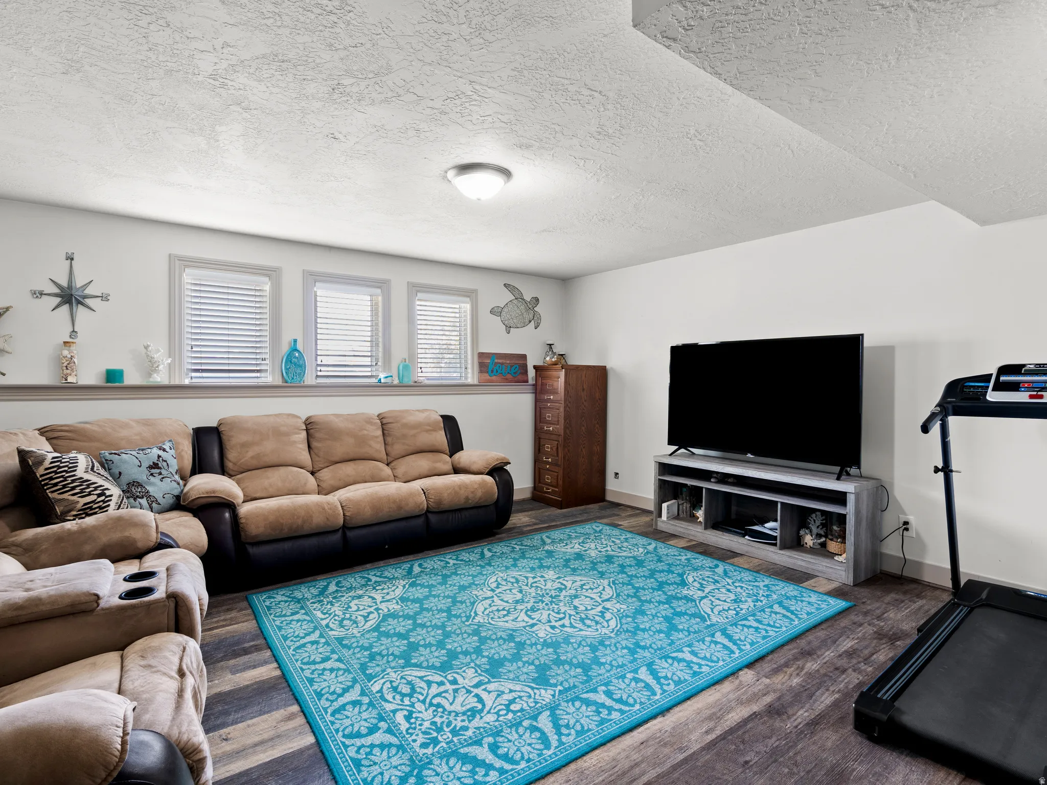 Living room featuring a textured ceiling and dark wood-style flooring