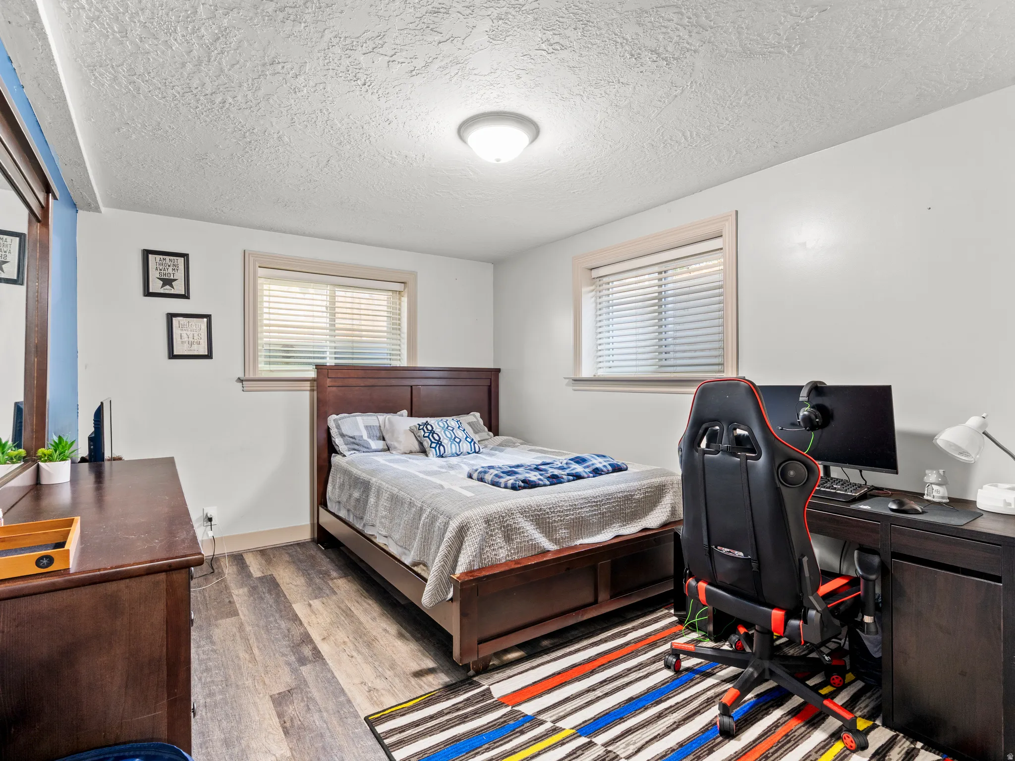 Bedroom with a desk, wood finished floors, and a textured ceiling